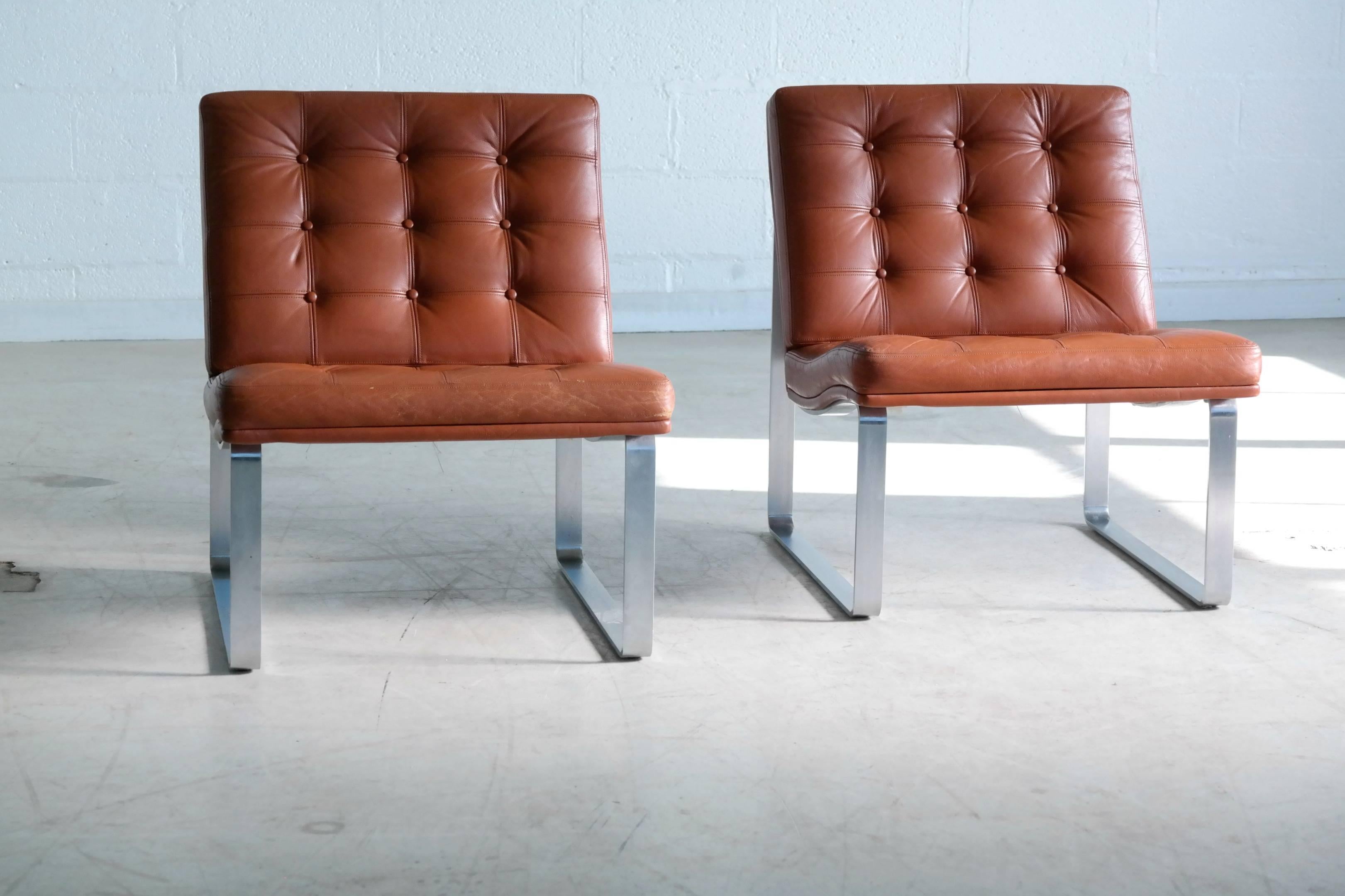 Stunning pair of lounge chairs in reddish brown leather on steel legs. Designed by Ole Gjerløv-Knudsen and Torben Lind as part of the Moduline series in 1961 and manufactured by France & Son. These chairs are a rare edition of Moduline which is