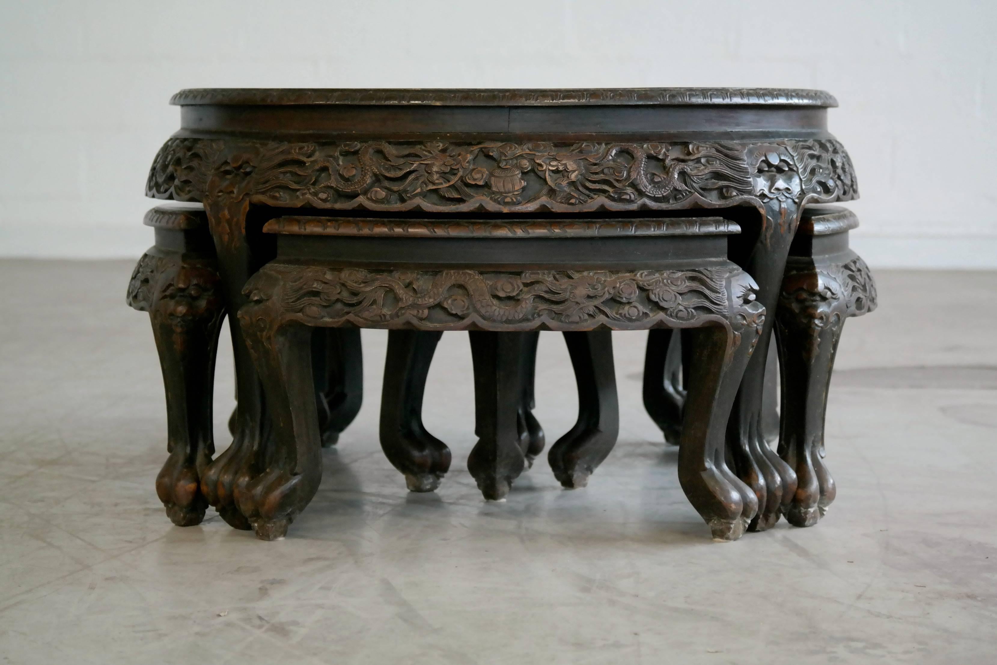 Beautiful hand-carved mahogany Chinese tea table with four stools that stores underneath the table. Manufactured by George Zee and Company in 1960 - manufacturer's label attached to underside of table.
