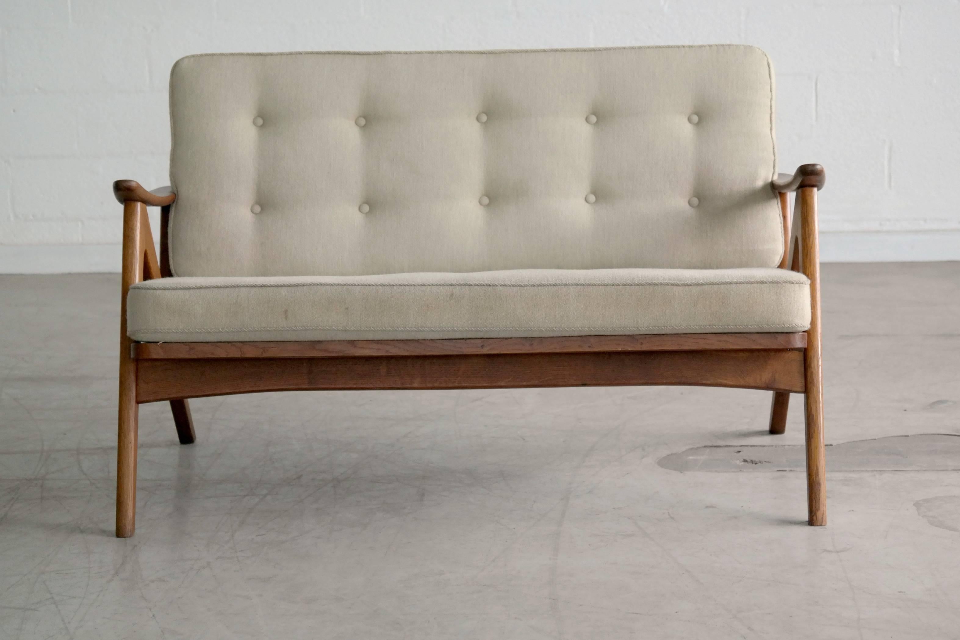 Great 1960s easy style sofa in the style of Hovman-Olsen. Smaller proportions more like a love seat with two long cushions instead of the individual cushions often used on easy sofas. All solid teak with wool upholstery.