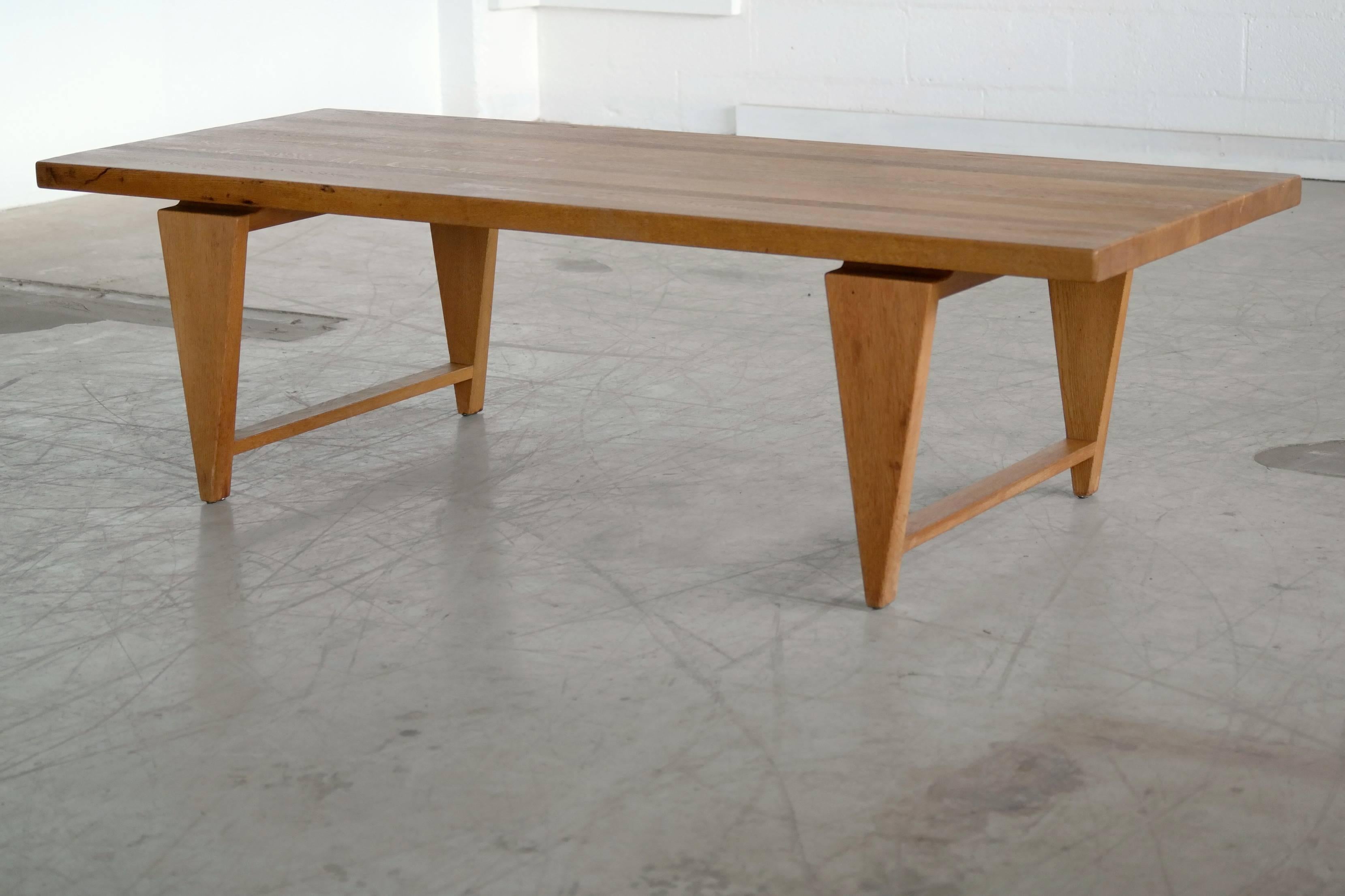 Coffee table by Illum Wikkelsø with distinctive triangular legs and floating top. In solid golden oak, this table has a strong, graceful presence with it's rather solid upper resting almost tip-toeing on it's four points.