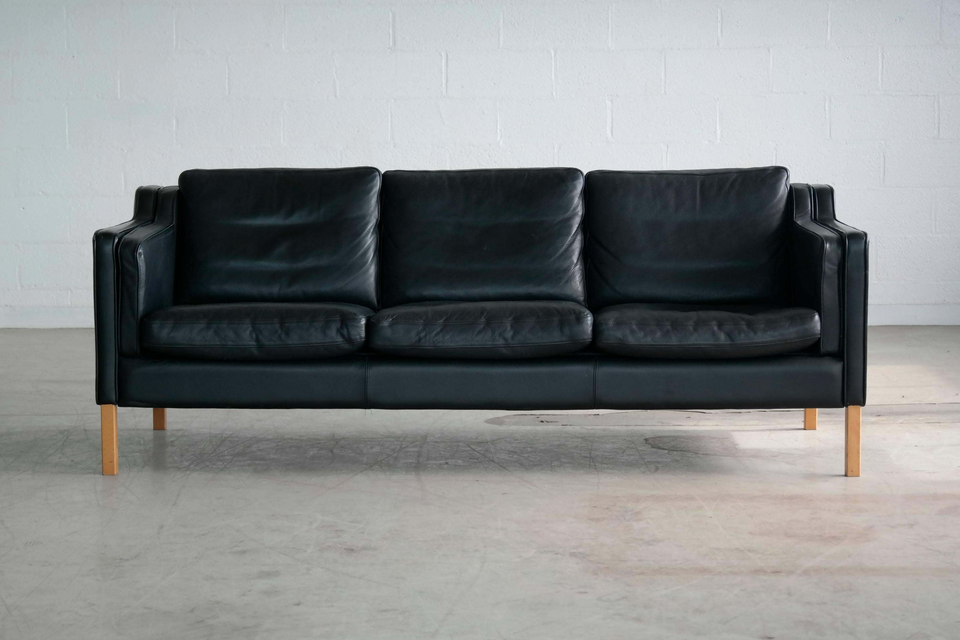 Very elegant and comfortable Classic Borge Mogensen style sofa model 2213 in black leather by Stouby Polsterfabrik of Denmark. High quality leather over a beech wood frame and legs. Cushions are top filled with down. Nice worn in quality with some