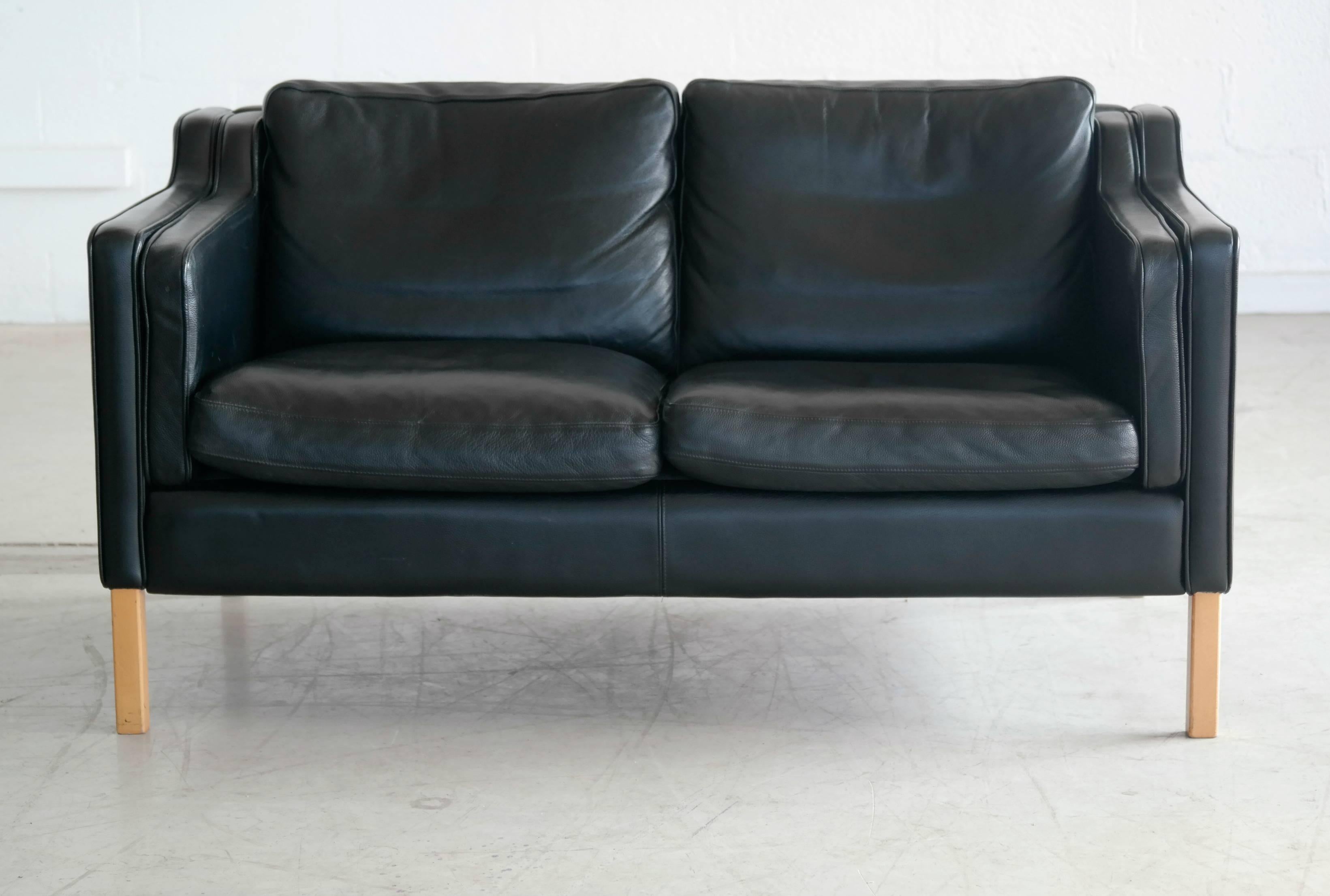 Very elegant and comfortable Classic Børge Mogensen style sofa model 2212 in black leather by Stouby Polsterfabrik of Denmark. High quality leather over a beechwood frame and legs. Cushions are top filled with down. Nice worn in quality with some