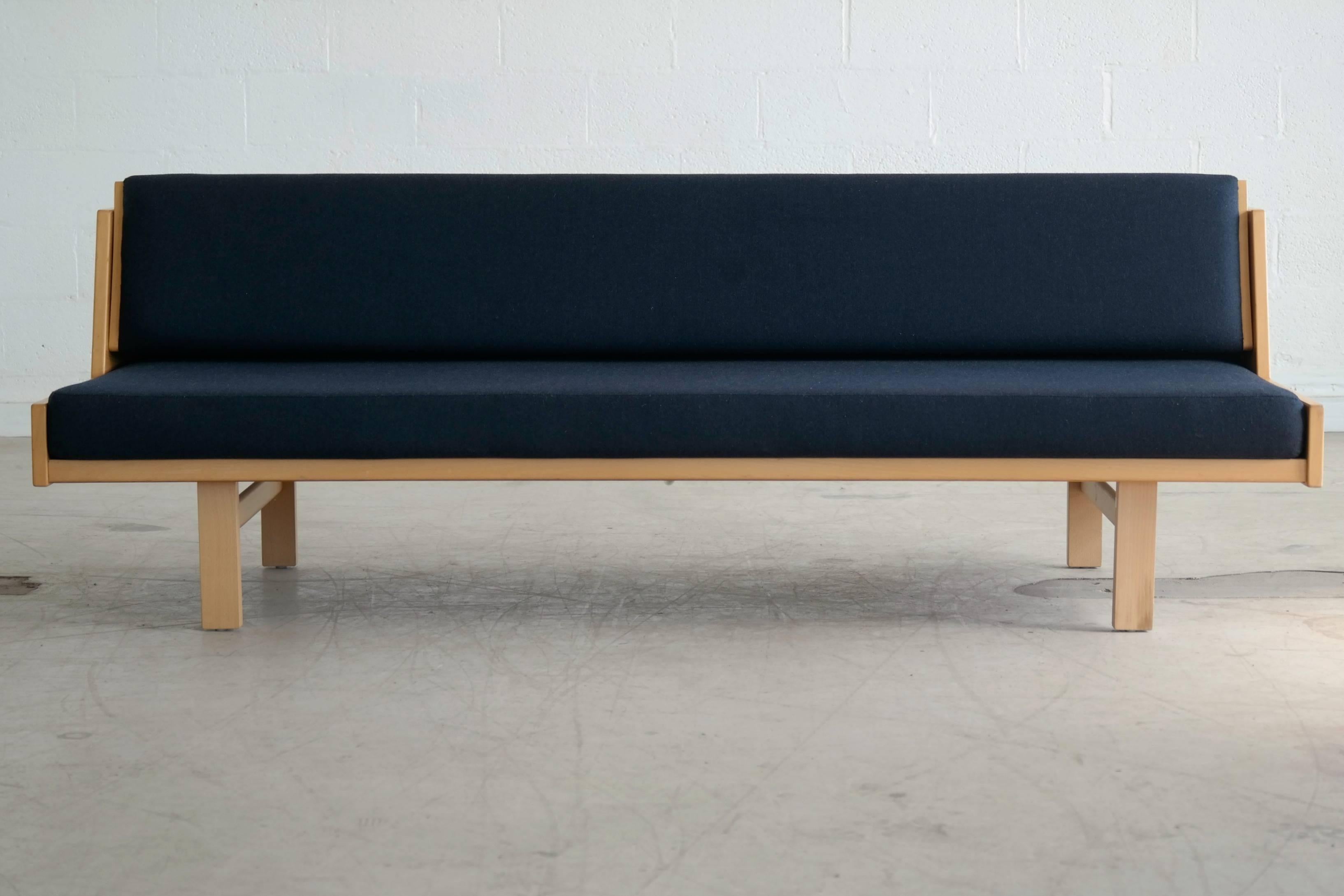 Classic iconic daybed designed by Hans Wegner and manufactured by GETAMA .The frame is made from beech and is upholstered in blue wool fabric. The backrest of the sofa can be raised, giving you added storage space for pillows and blankets. Designed