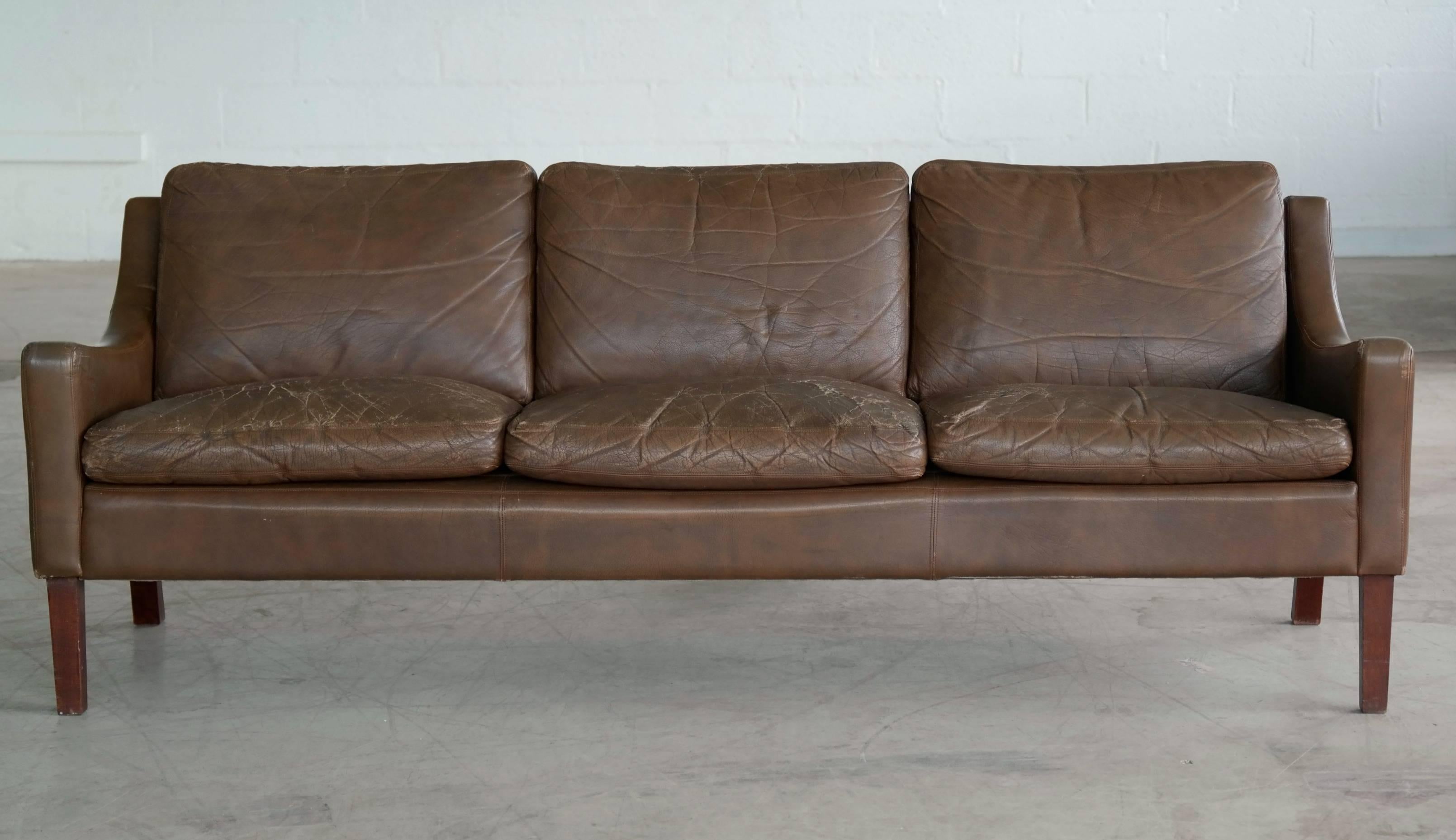 Very elegant low slung brown leather Danish Mid-Century sofa in the style of Børge Mogensen. Solid and sturdy construction on a beech frame and legs. The leather shows plenty of the wear and patina throughout giving it that sought after distressed