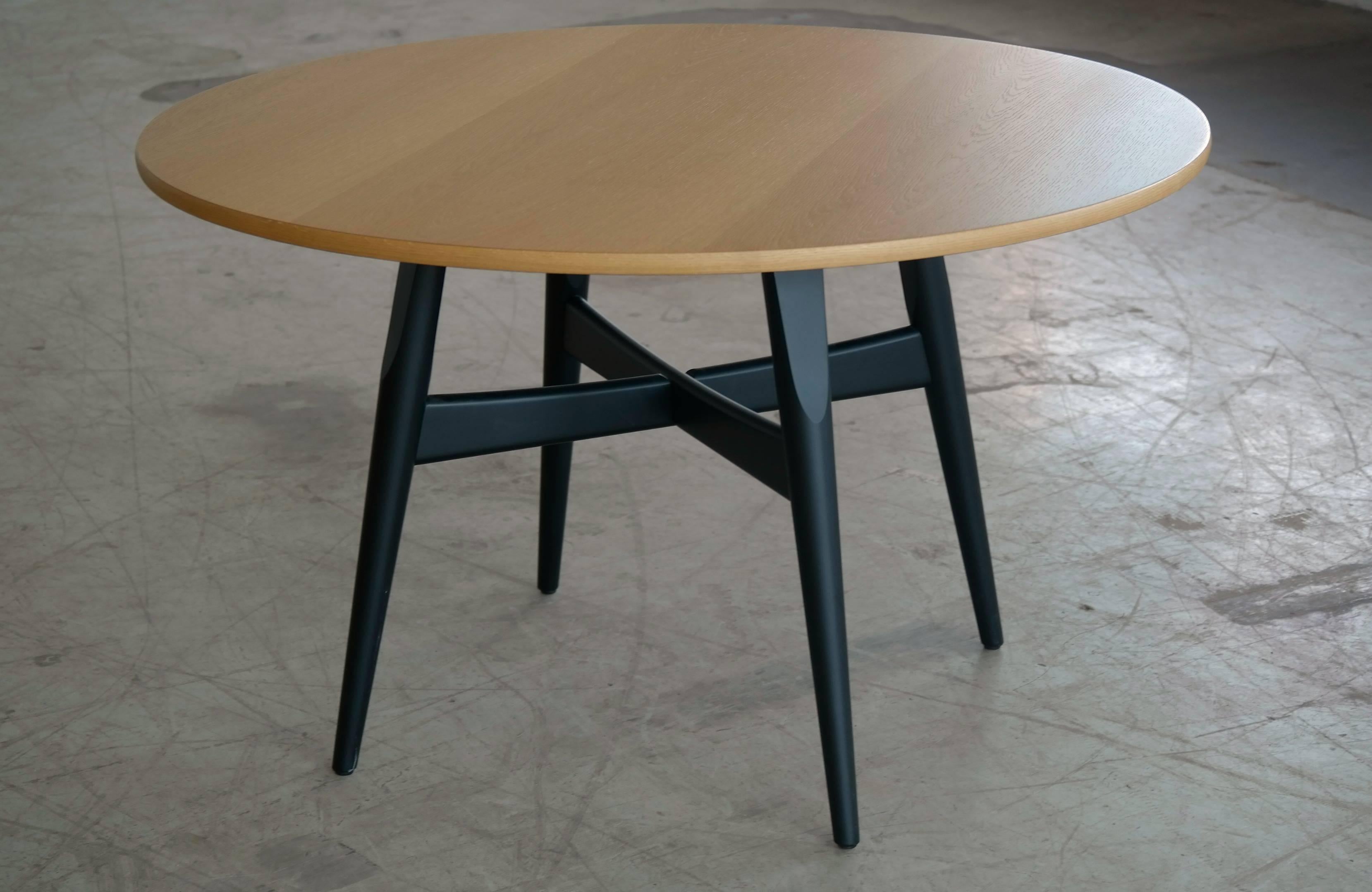 Beautiful and very functional round dining table made of oak veneer on a base of black lacquered wood base in black lacquer. Designed by Hans Wegner in 1970 and carrying on the tradition from some of his earlier designs. Produced by GETAMA for whom