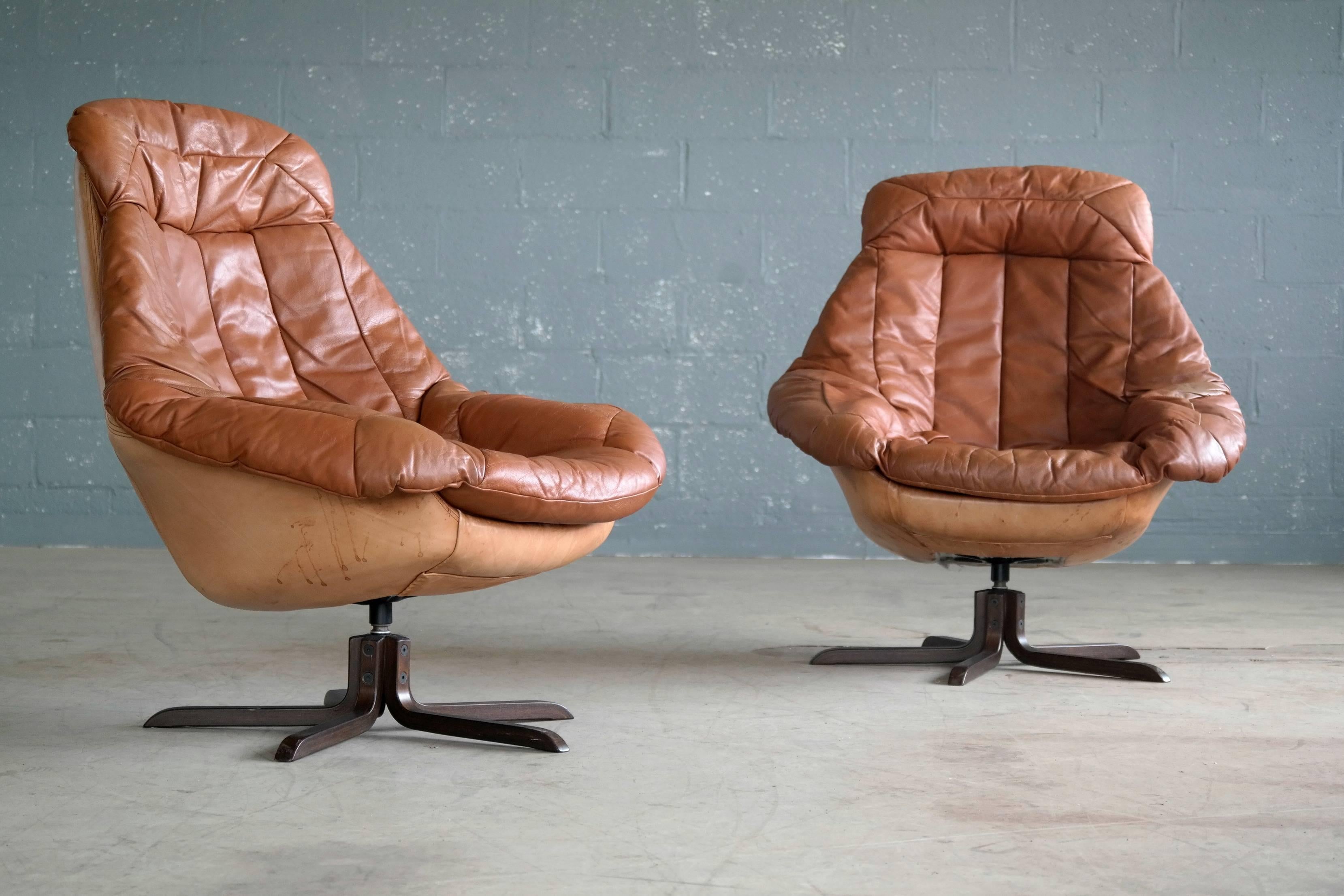 Great high back swivel lounge chairs designed by H.W. Klein for Bramin Mobler, Denmark ca. 1970. Upholstered in a light cognac colored tufted leather and mounted on five-star wooden swivel base with rosewood stain. Magnificently comfortable, created