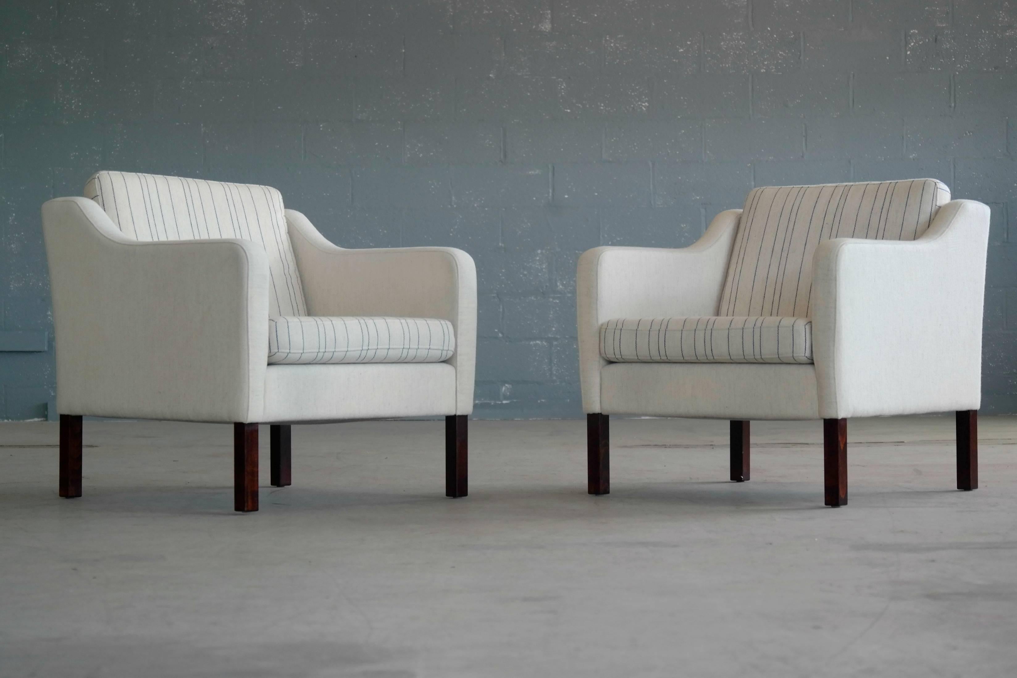 Very elegant pair of lounge chairs in the style of Borge Mogensen's Model 2421. These chairs by Mogens Hansen were designed in the 1960s and produced, circa 1970. The chairs have stained beech wood legs and are covered in a luxurious cream white