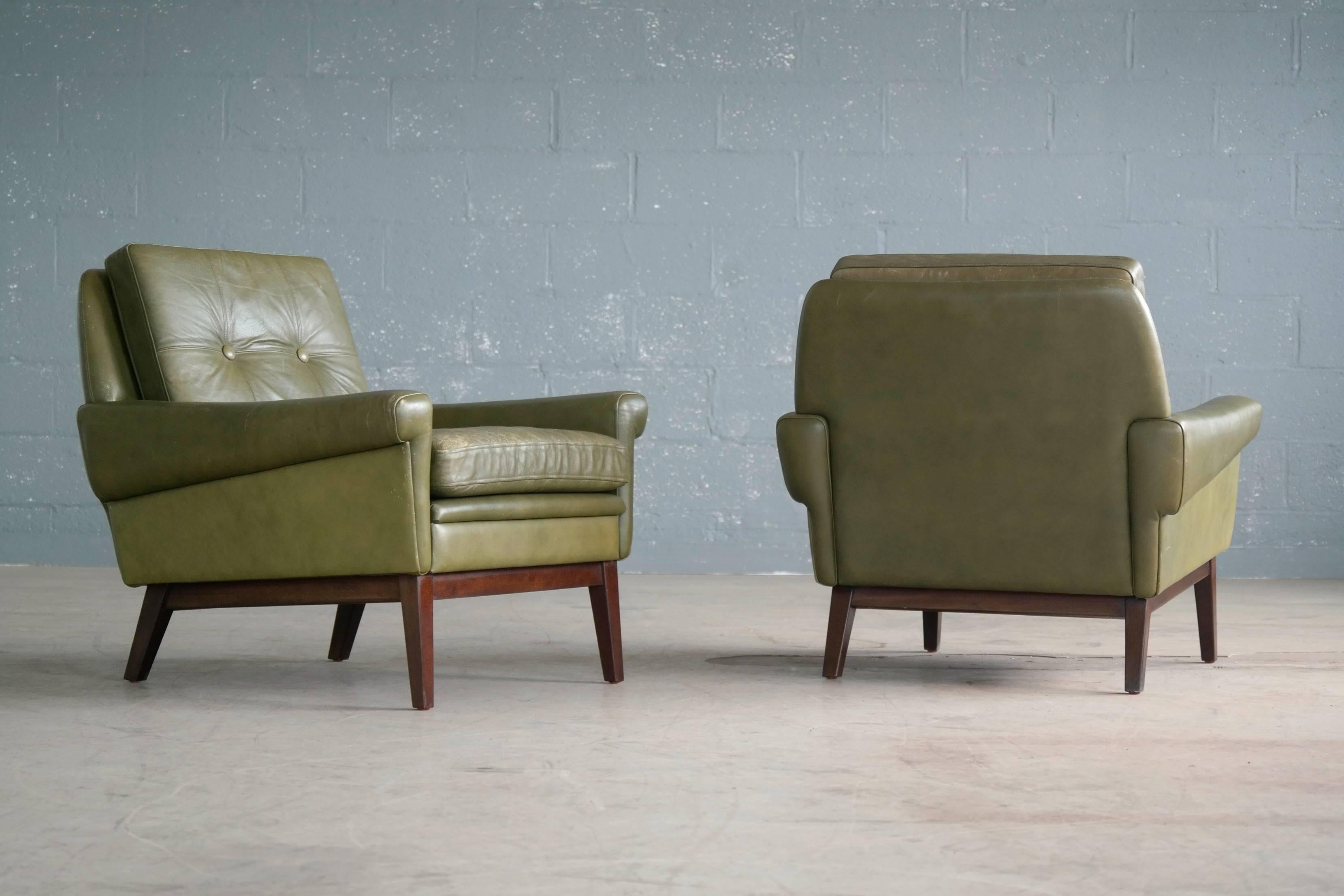 Super stylish pair of 1960s lounge chairs in supple dark green leather by Svend Skipper. Very sought after iconic Skipper design with loose cushion on rosewood stained bases of beech. Perfectly worn and with great patina and little color variation