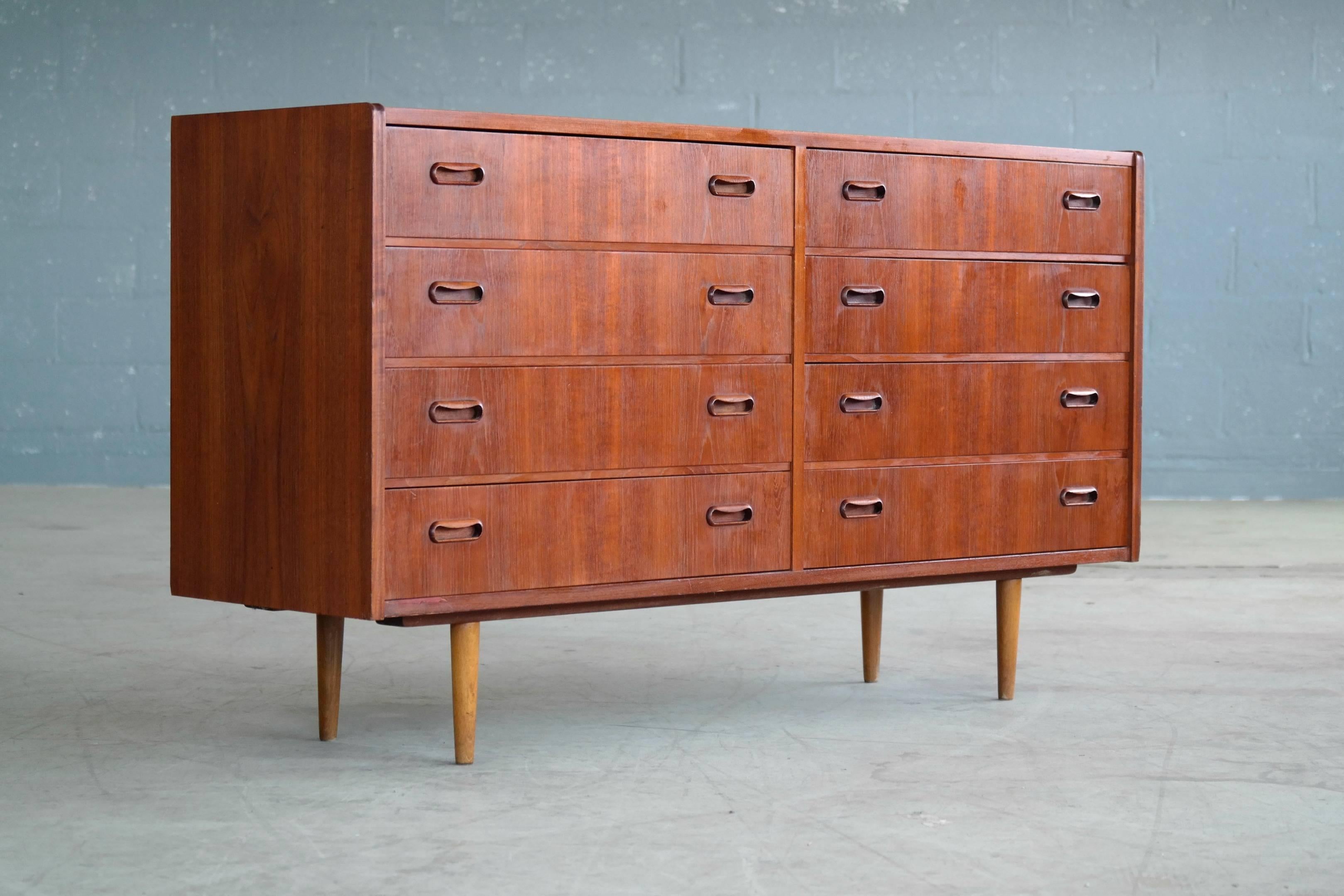 Rare to find 1960s Danish modern teak double dresser. Nice bookmatched wood grain. Drawers are constructed with dovetail joinery and are complimented by the finely carved hand pulls giving this simple dresser an elegant touch. Tapered beech wood