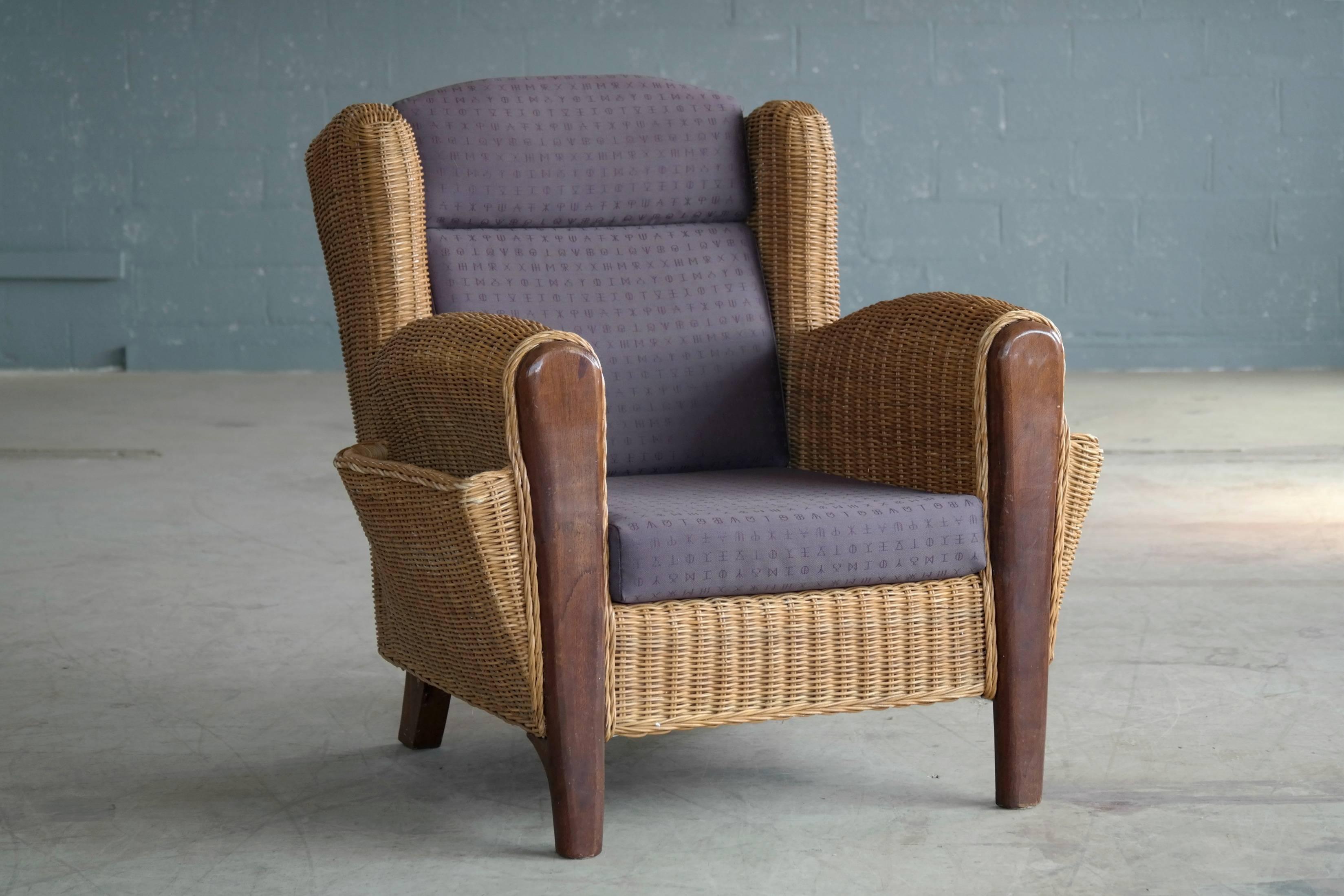 Unusual and comfortable and very decorative Danish wicker arm og lounge chair with built in magazine pockets on the sides. Perfect for a relaxing afternoon on the porch or in the sun room. Cushions are firm and upholstered in a brown fabric. Chair