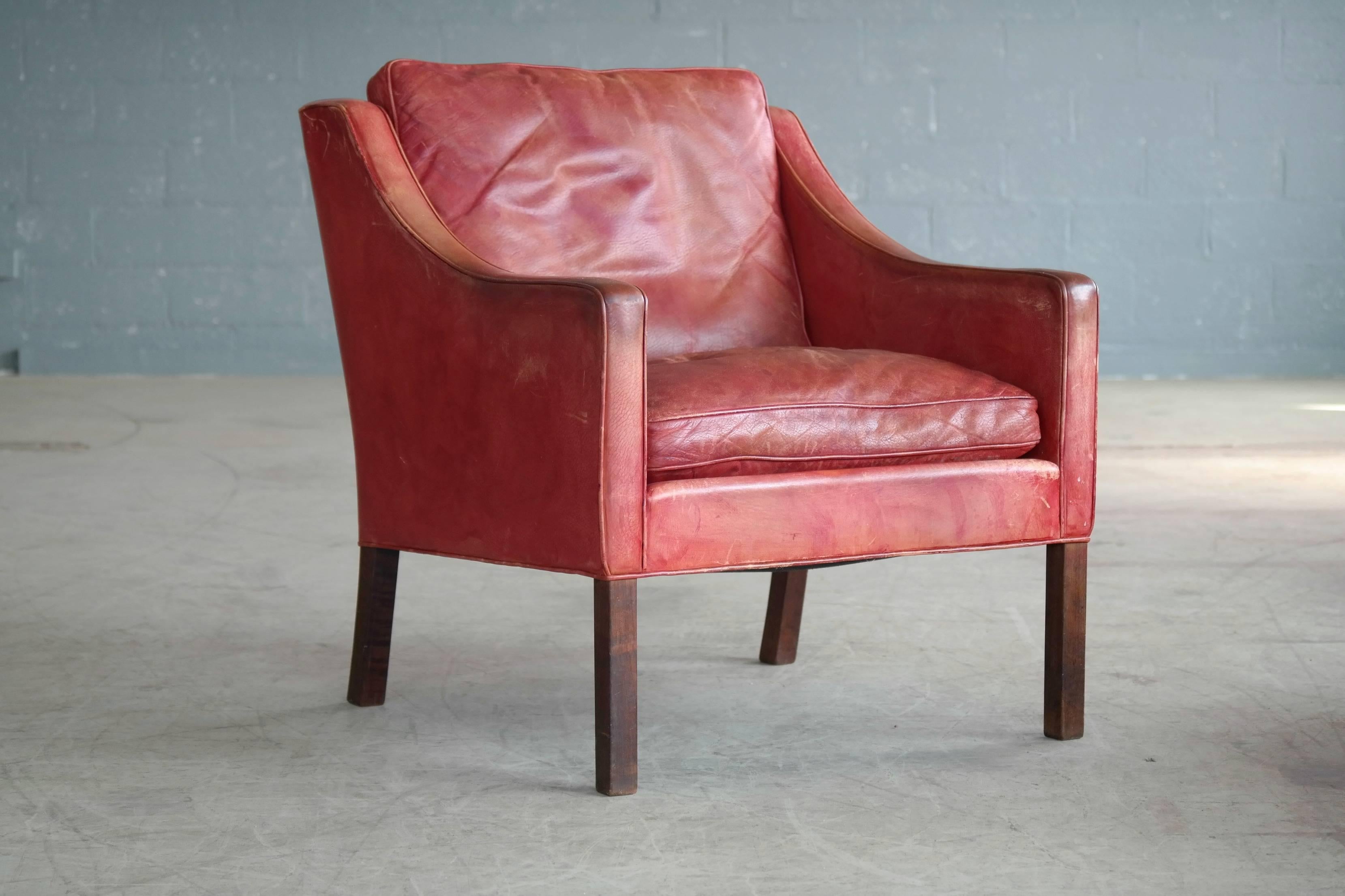 Børge Mogensen lounge chair model 2207 in red leather For Fredericia. This is the real deal in a rare to find color. Admirable patina throughout with some color fading and wear, but overall very good condition. Supercool and very comfortable accent