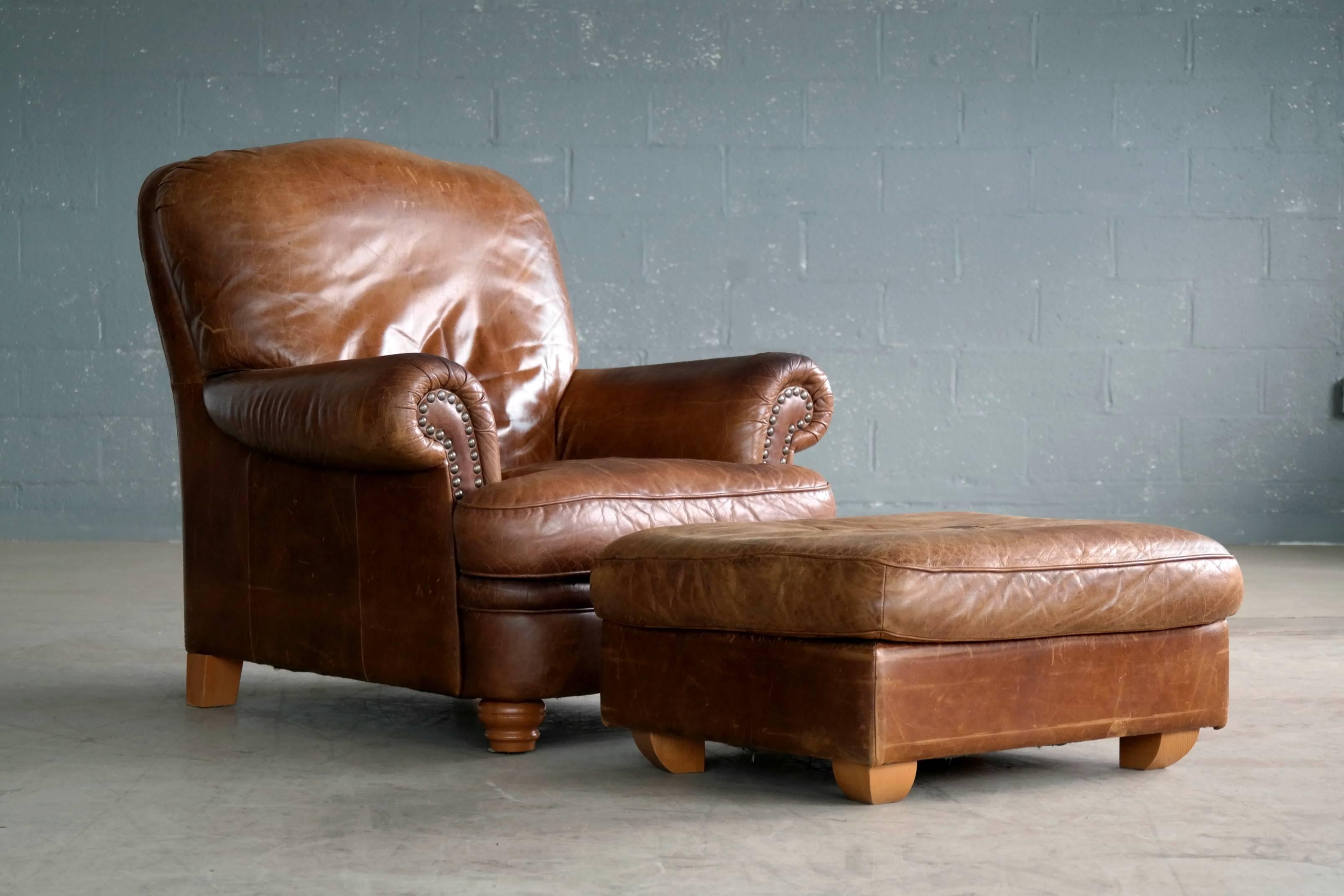 Ultimate in comfort and style, Danish Mid-Century large size cognac color leather club chair with ottoman. Admirable patina and wear. Some minor crazing to the armrests and a small negligible tear to top the left armrests. A few small stain to the