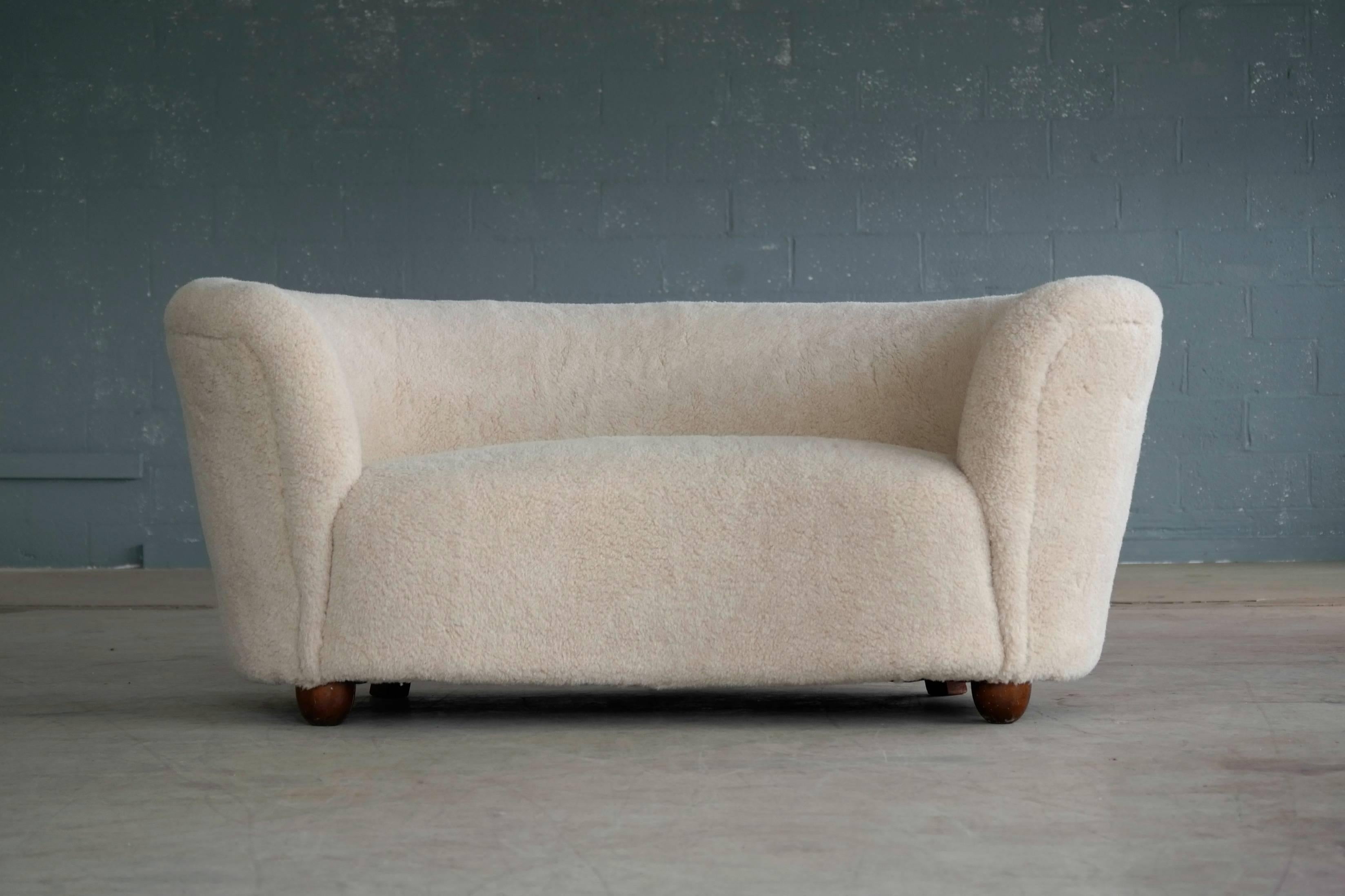 Banana shaped Viggo Boesen style curved two-seat sofa or loveseat attributed to Slagelse Møbelværk. This sofa will make strong statement in any room. Beautiful round lines and iconic ball feet. Fully refurbished and newly upholstered with beige