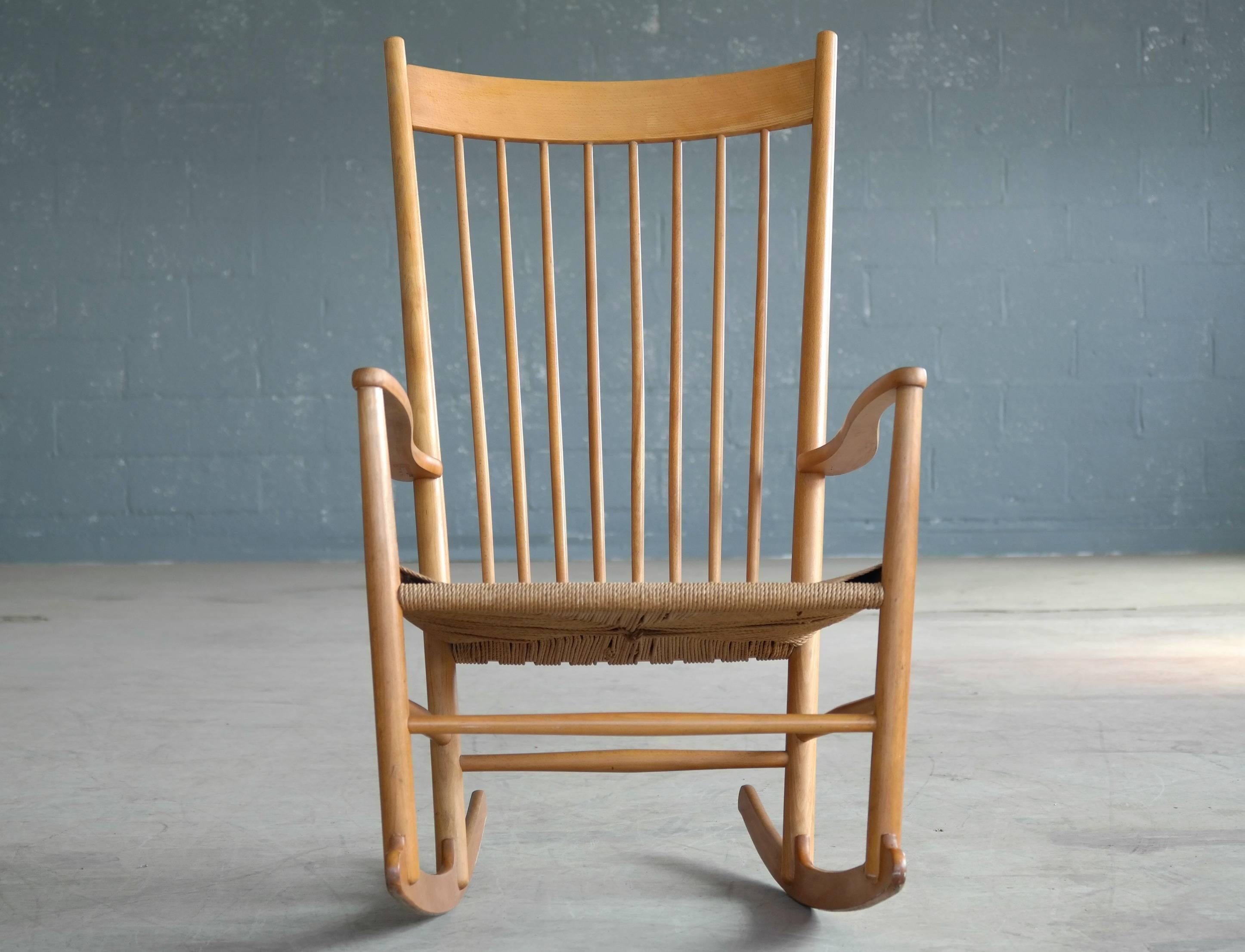 An early 1950s original Hans Wegner J16 Shaker inspired rocking chair with a spindled back, curved armrests in beech and papercord seat all in its original finish. Made by FDB Møbler, Denmark. Good overall condition with some natural age wear and
