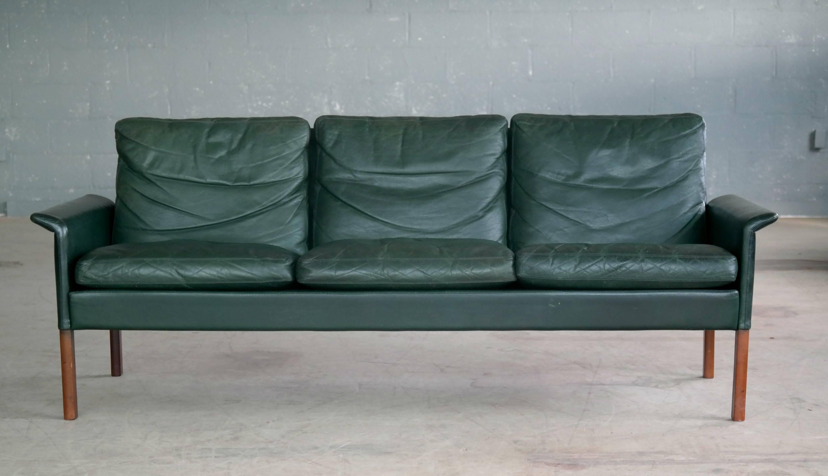 Superbly elegant three-seat sofa designed by Hans Olsen in the 1960s for CS Mobler in Glostrup, Denmark. Covered in supple top grain leather with nice patina and in a very attractive hard to find racing green color. Legs in solid teak. Overall