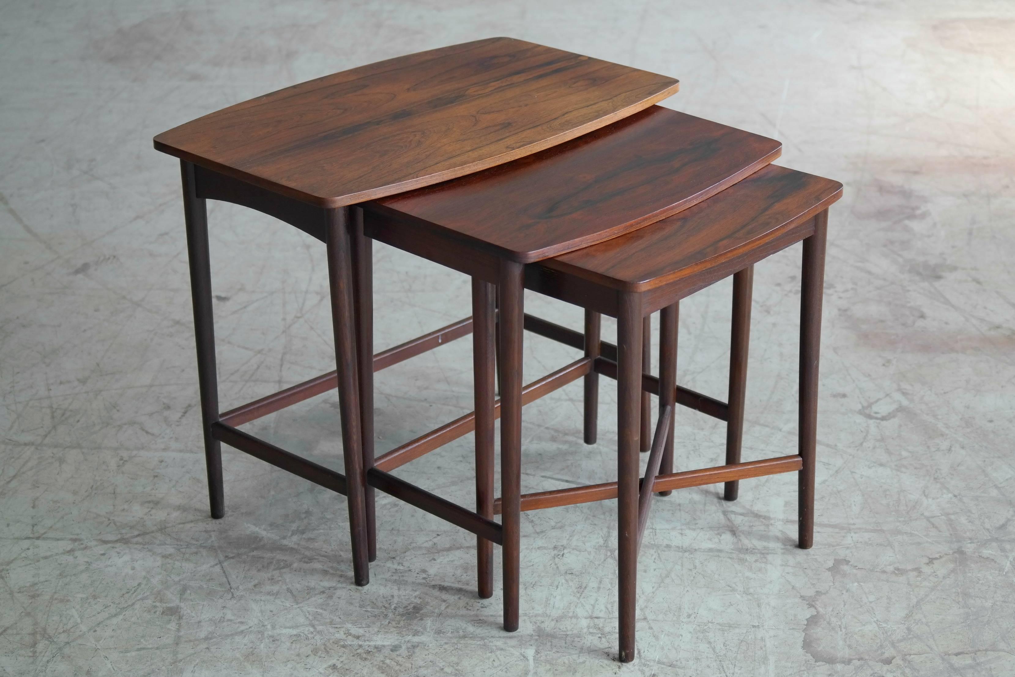 Very nice set of three Danish nesting tables in rosewood in the style of Johannes Andersen. The tables vary slightly in color with the middle table being slightly darker, while the other two tables have faded a little bit due to sun exposure. Some