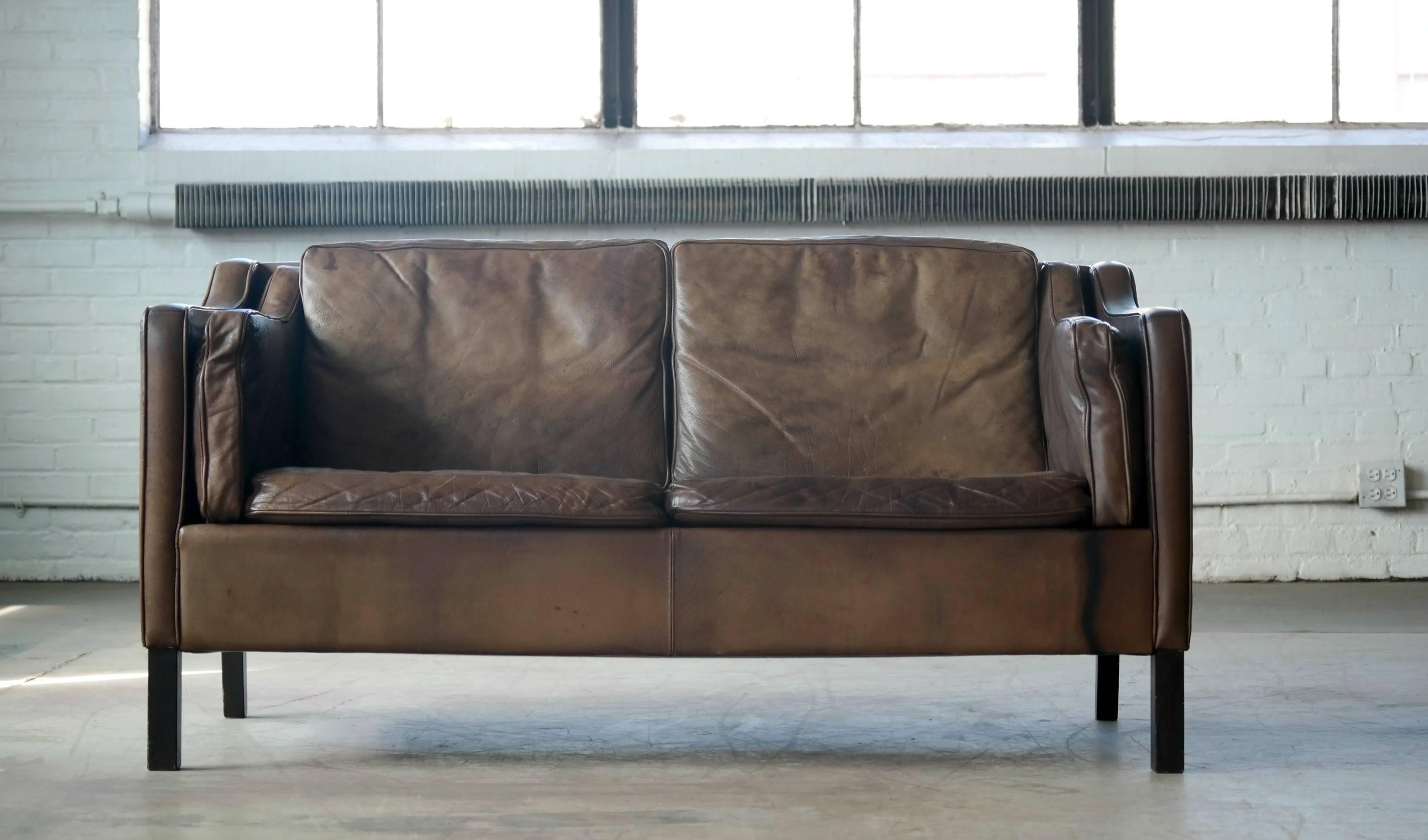 Classic Borge Mogensen style two-seat sofa or loveseat in the style of Borge Mogensen produced by Mogens Hansen. Has achieved that admirable patina that only the combination of aniline buffalo leather and time can produce. Fantastic patina and