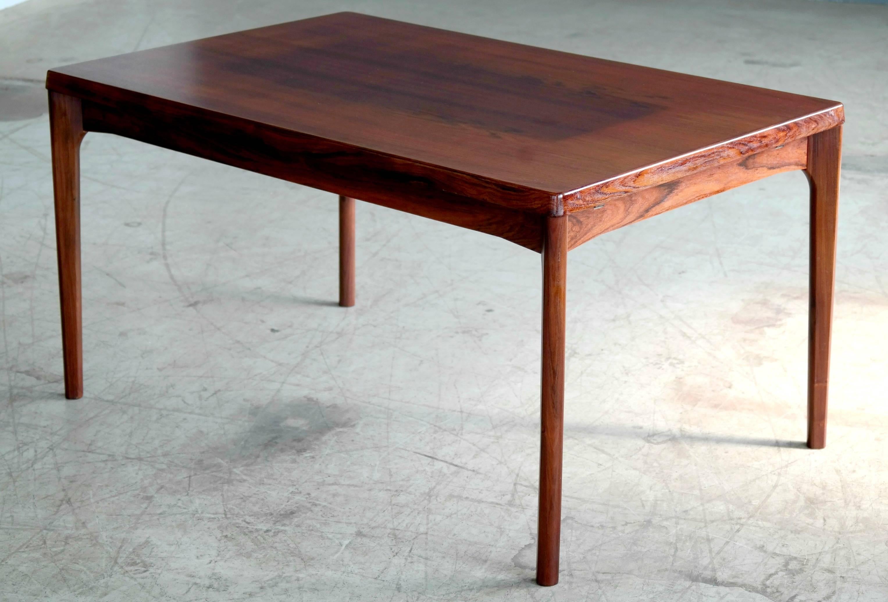 A stunning rosewood draw leaf dining table by Henning Kjaernulf for Vejle Stole & Møbelfabrik in the 1960s. Features beautiful rosewood grain with solid thick edges and sculpted legs. Expandable with two draw leafs to comfortably seat of ten