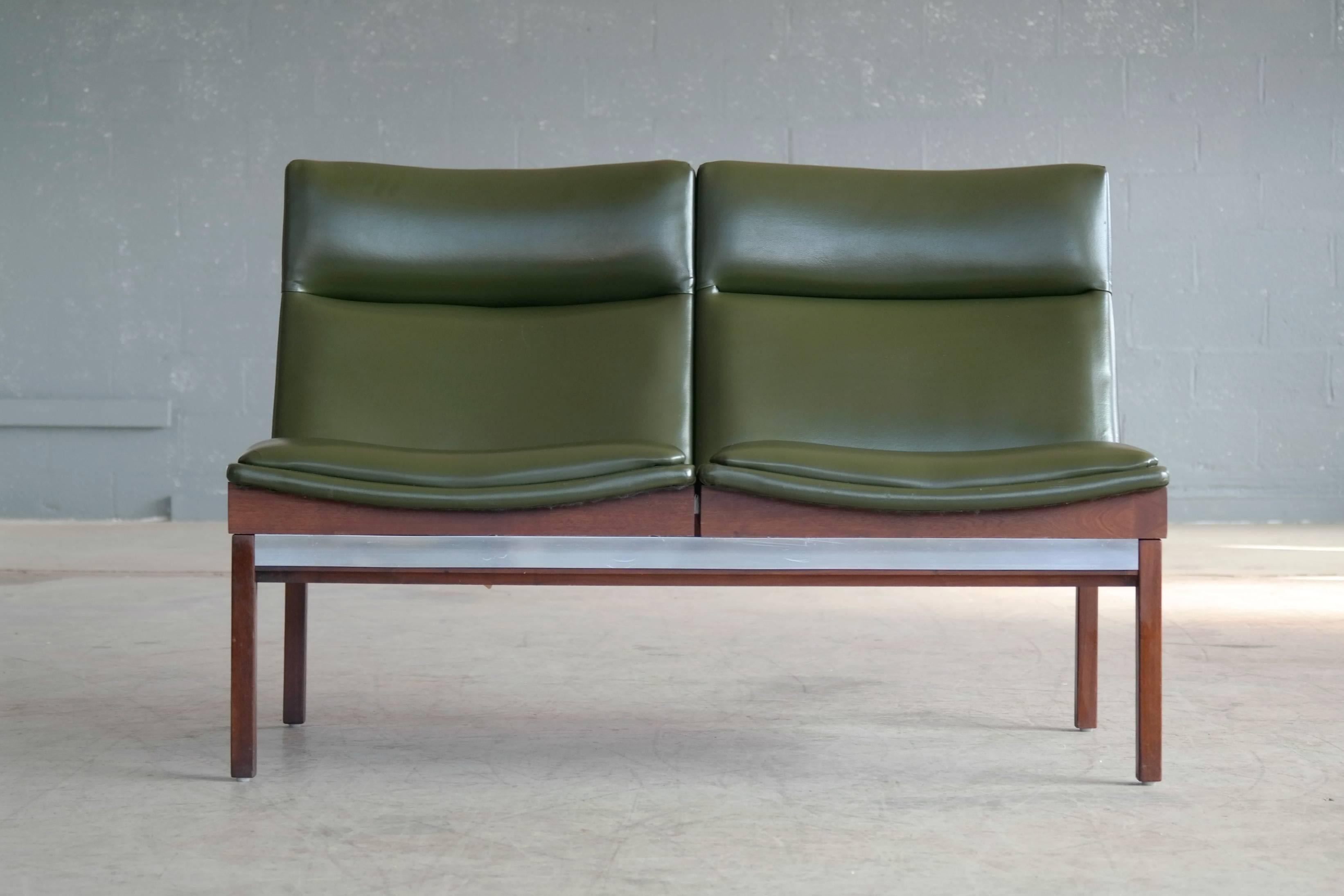 Very cool modular two-seat sofa made in walnut with aluminium accents and covered in green Naugahyde designed by Arthur Umanoff in the 1950s for Madison Furniture Industries. Overall very good condition with a few small blemishes to the Naugahyde