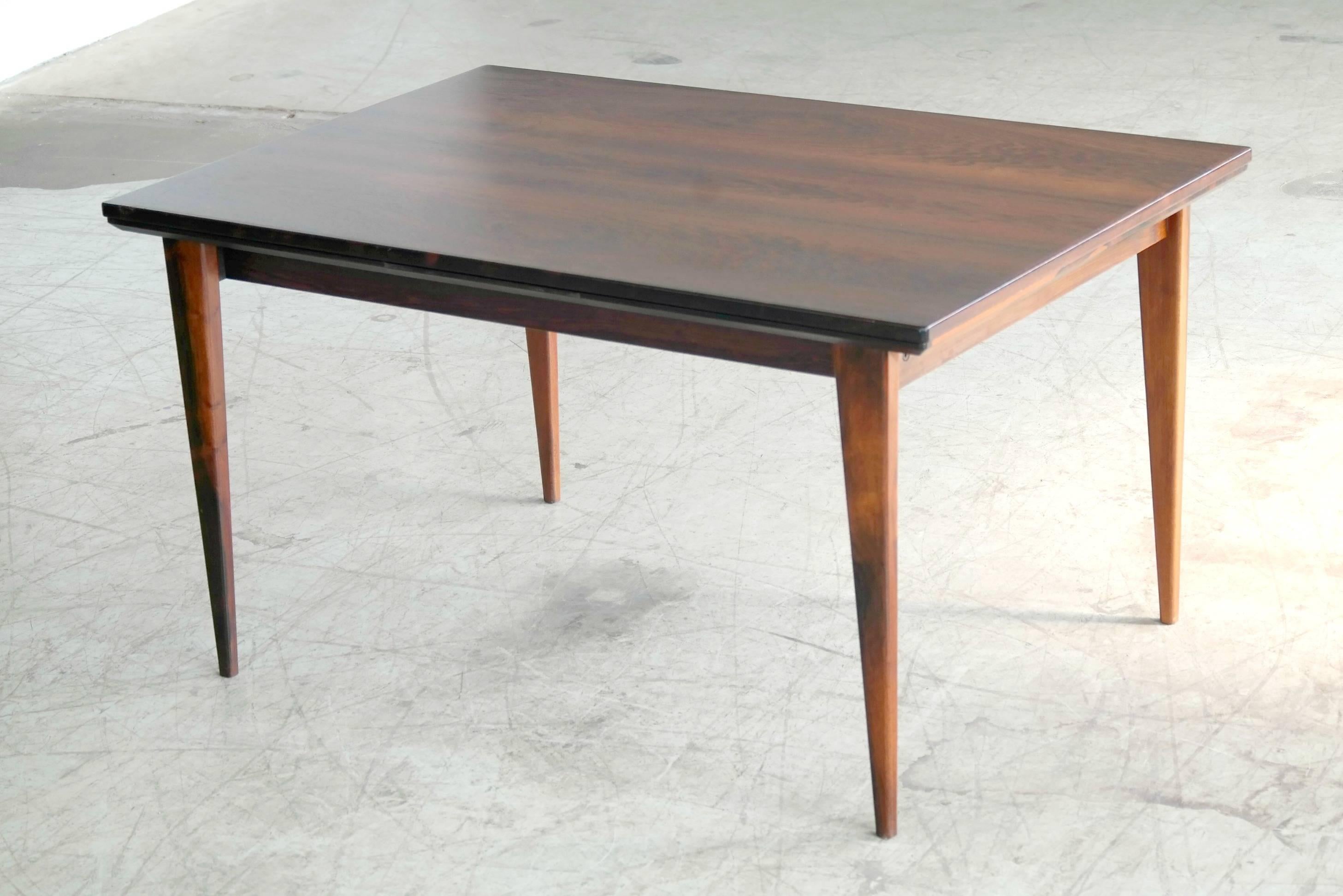 An exquisite rosewood dining table with stunning grain and two extension leaves made by Gudme Mobelfabrik, Denmark in the 1960's. 

It measures 54.5" long without the leafs. There are two leafs stored inside the table. With both of them