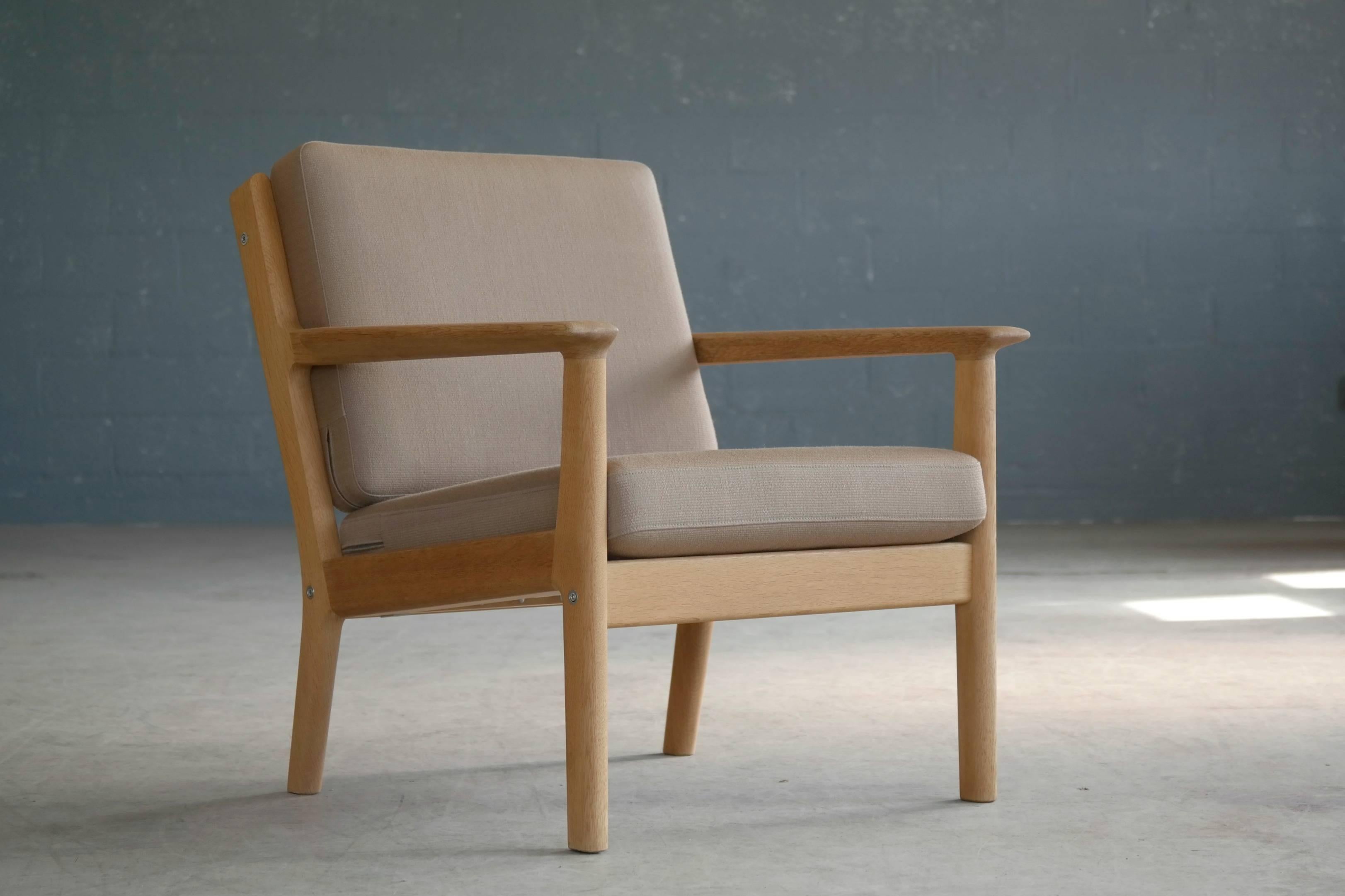 Elegant Hans Wegner designed easy chair made by GETAMA in the early 1970s featuring a solid oak frame and wool covered foam cushions. The cushions remain in their original wool. The chair is in excellent vintage condition with a nice patina. Very