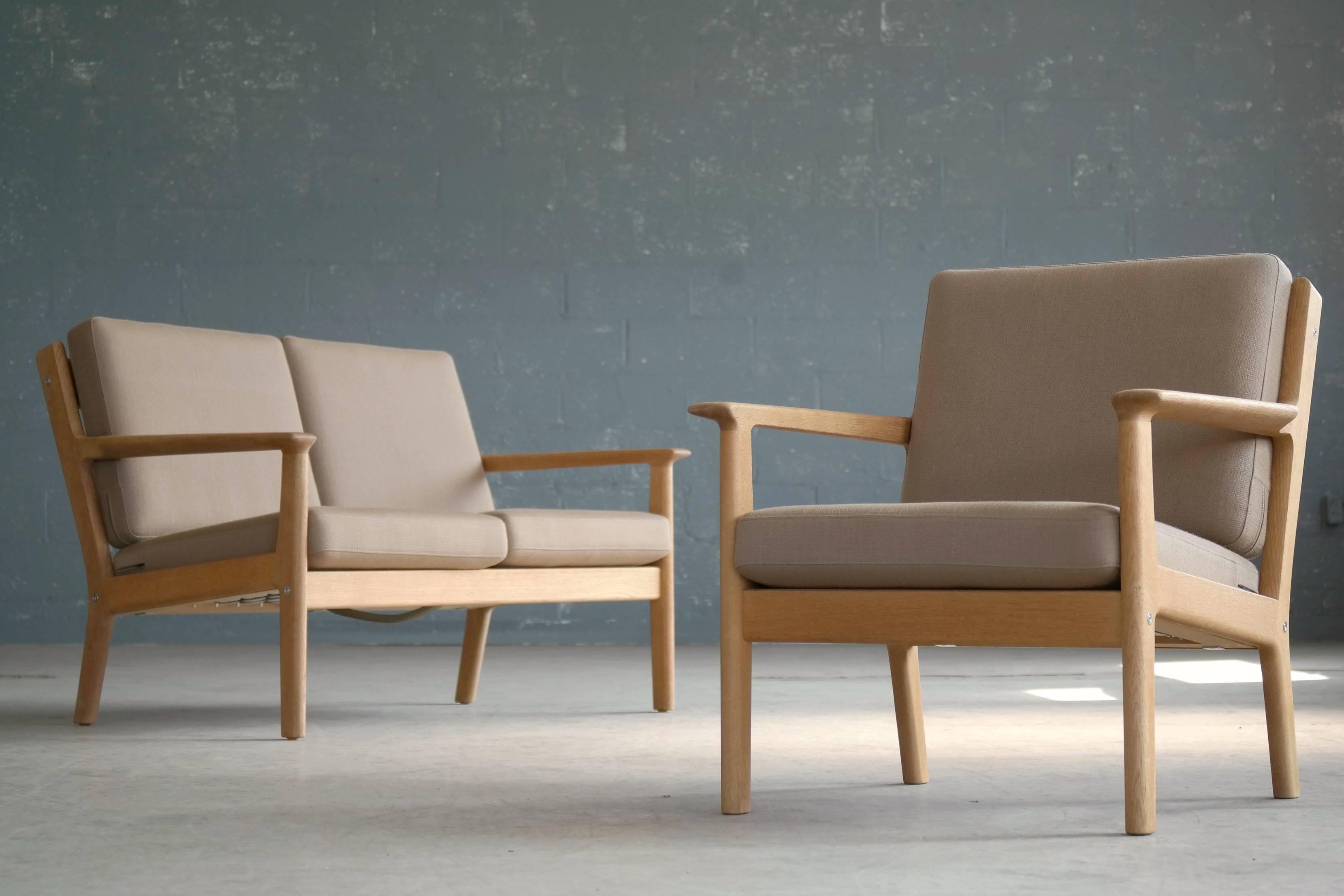 The model GE265 two-seat with matching easy chair were designed by Hans J Wegner for GETAMA in the early 1970s featuring a solid oak frame and wool covered foam cushions. The cushions remain in their original wool. The set is in excellent vintage