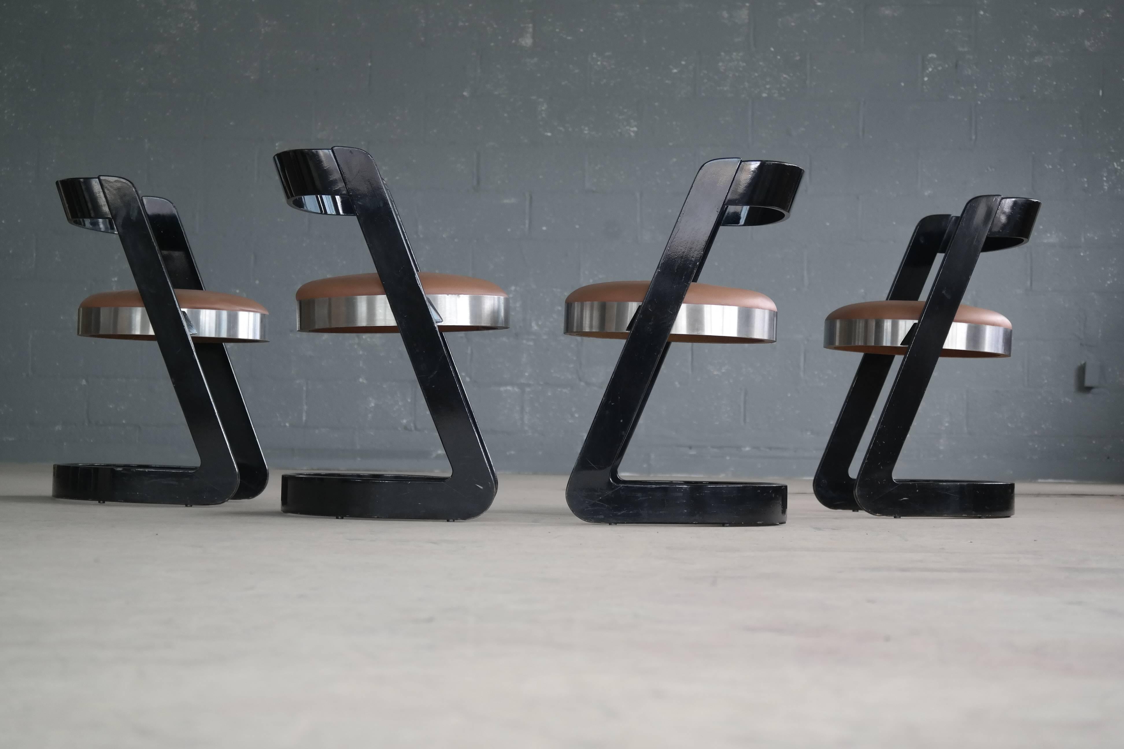 Superb set of four Willy Rizzo designed cantilevered dining chairs in black lacquered bentwood with seats of aluminum and cognac colored vinyl. Made around 1970 by Mario Sabot. The wooden structure is formed of two diagonal supports resting on a