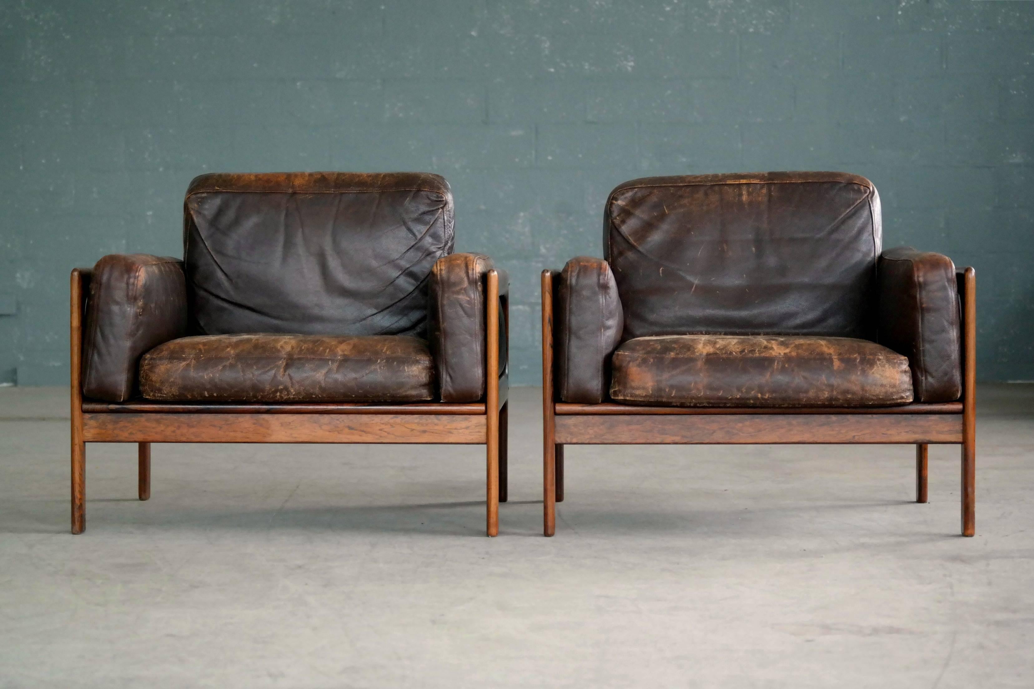 Fantastic and rare pair of easy chairs designed by Arne Wahl Iversen for Komfort Mobler of Denmark in the 1960s. Chocolate brown patinated leather with just perfect age wear on frames of Brazilian rosewood. The wood is in excellent condition with