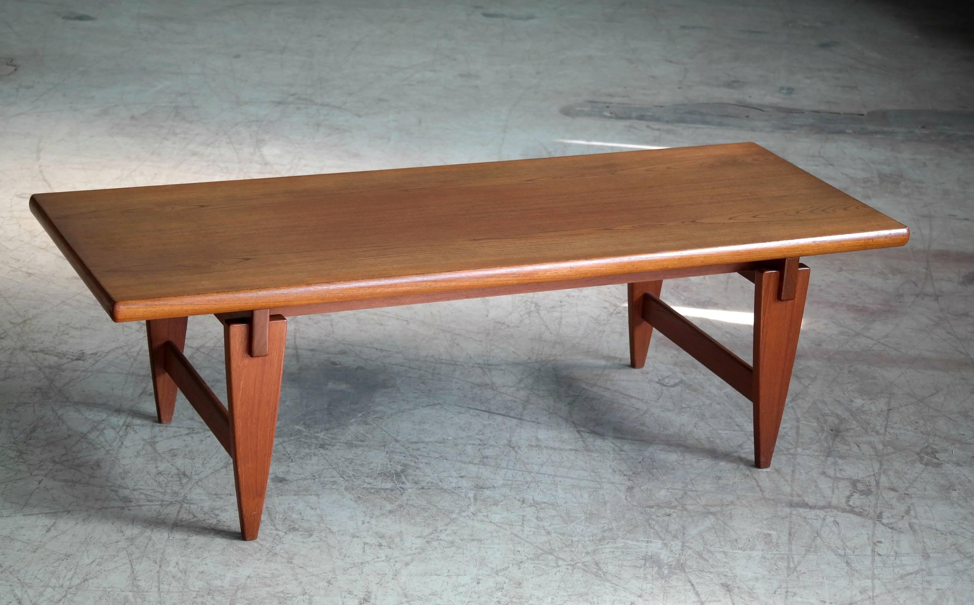 Beautiful coffee table by Illum Wikkelsø with distinctive triangular legs and floating top. Made in 1960s with a teak veneers top resting on a solid teak base and legs. This table has a strong, graceful presence with its rather solid upper resting