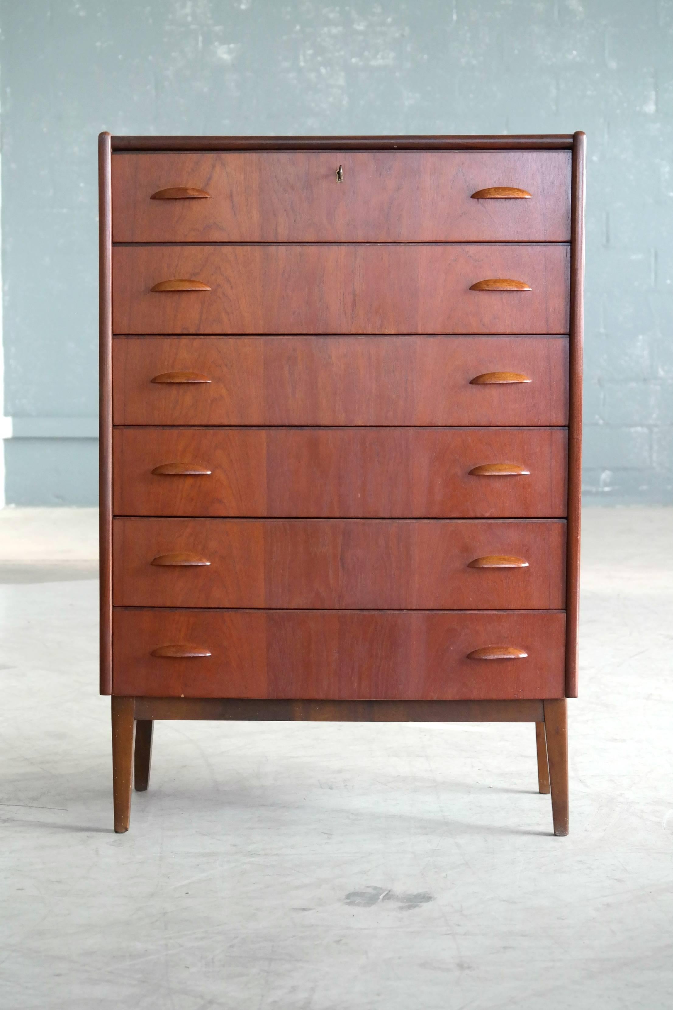 Beautiful bow-front Danish teak high-boy dresser or chest of drawers designed by Kai Kristiansen in the 1960s. Teak veneer with edges of solid teak and elliptical pulls carved from solid teak raised on solid tapered teak legs. All drawers solid ply.