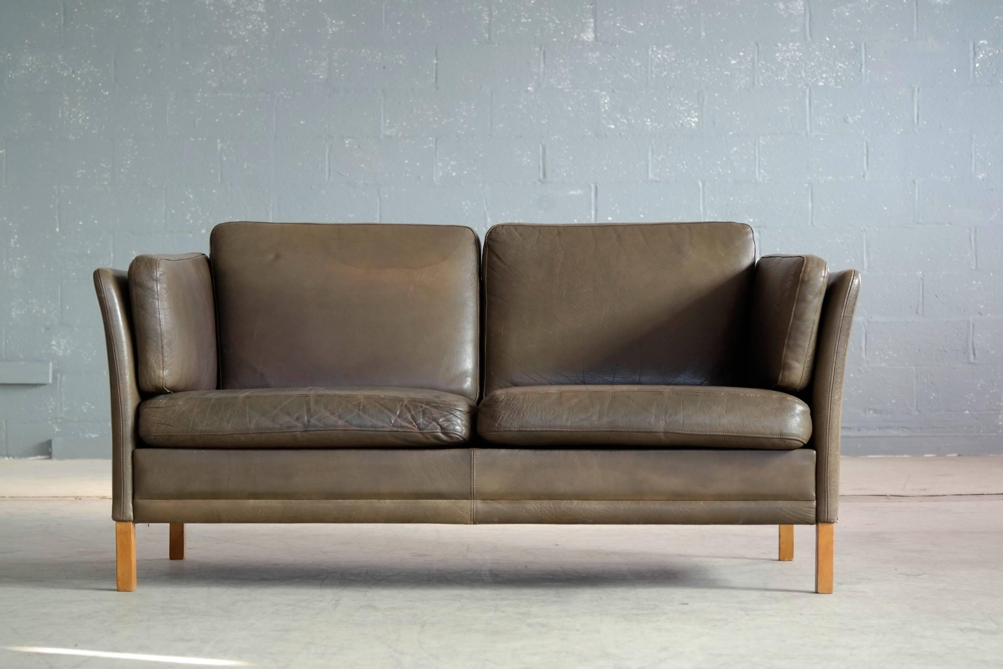 Classic Borge Mogensen style loveseat in dark olive colored buffalo leather designed by Georg Thams for Vejen Polstermobelfabrik, Denmark. Very nice quality leather with great patina and normal age wear. Cushions are foam filled and legs are natural