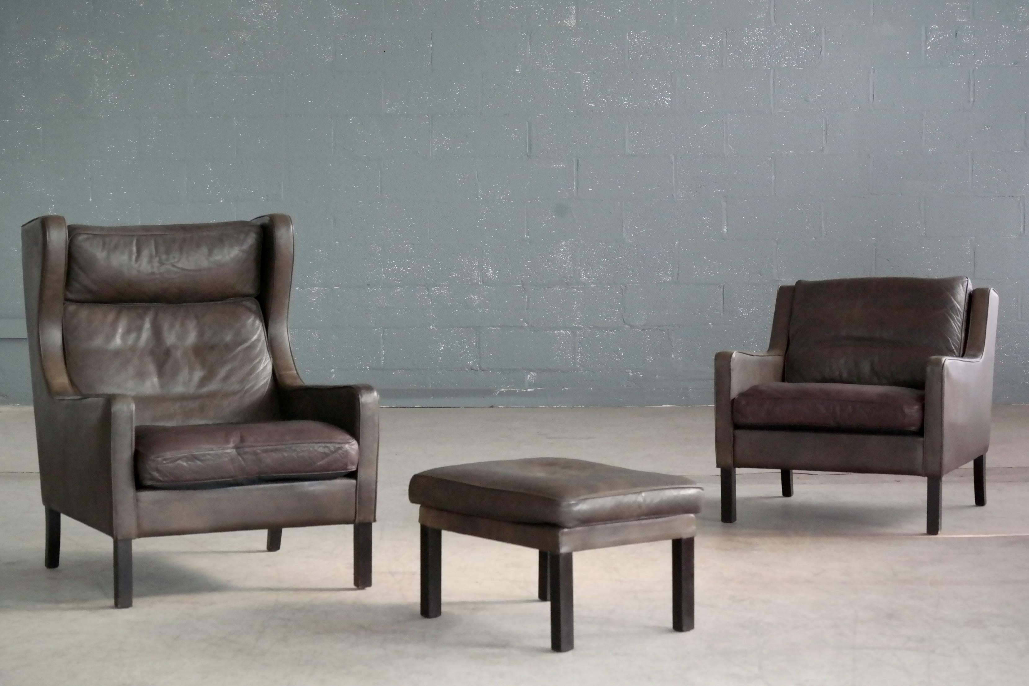 Classic Børge Mogensen style pair of high and low back lounge chairs with ottoman in dark olive colored leather designed by Georg Thams for Vejen Polstermobelfabrik, Denmark. Very nice quality leather with great patina and age wear including a