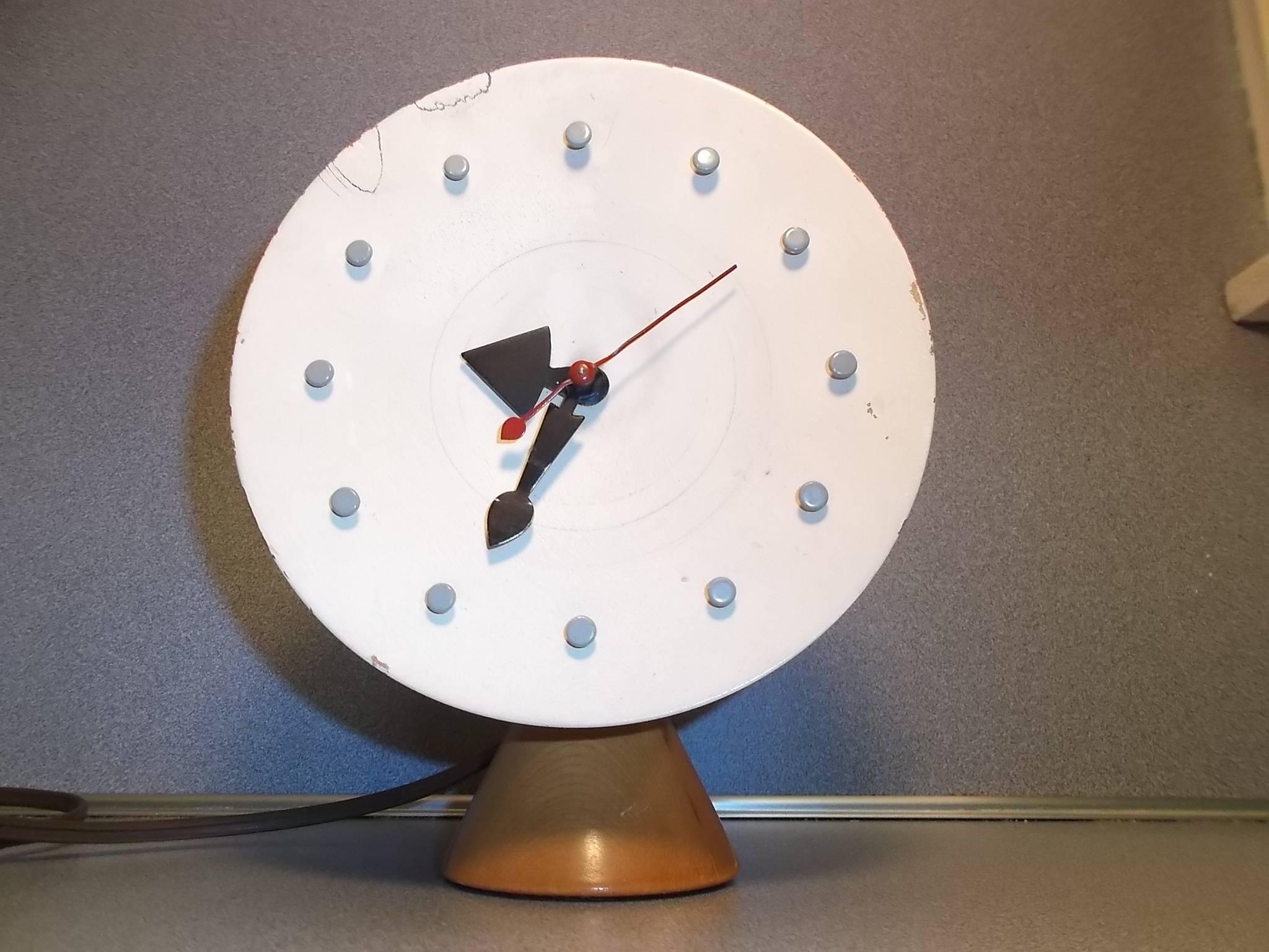 This is one of the rarer table clock versions to find by George Nelson. It features a white painted concave wooden face with black wood casing, and natural wood conical base. It has all of its orig. hands, and small grey thumbtack like hour markers.