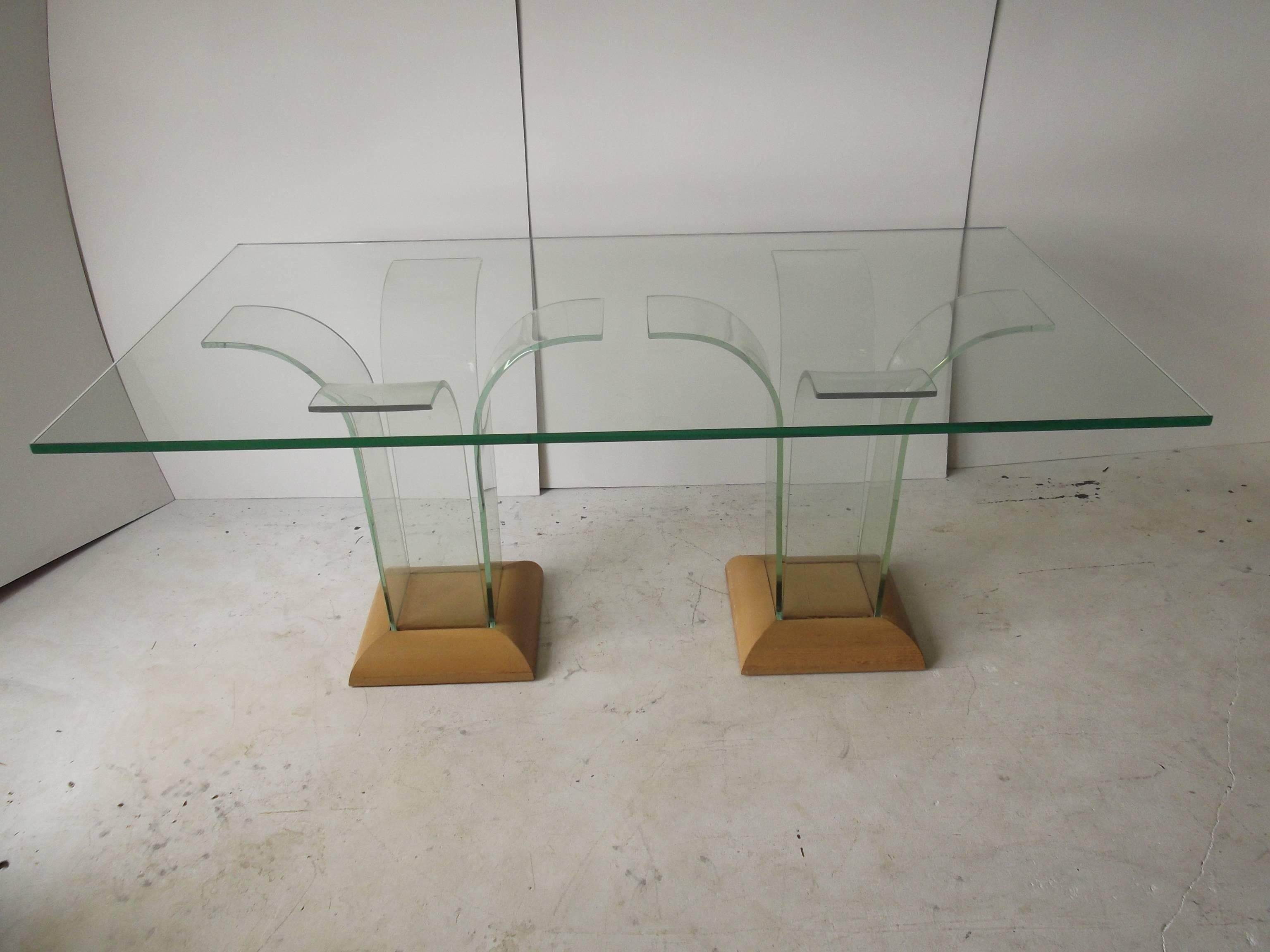This is an exceptional dining table in bent glass coming off the Art Deco period, circa 1940. It is for Modernage, by Ben Mildwoff. It is comprised of two pedestals, each with four pieces of bent glass, that suspend a glass tabletop. It has original