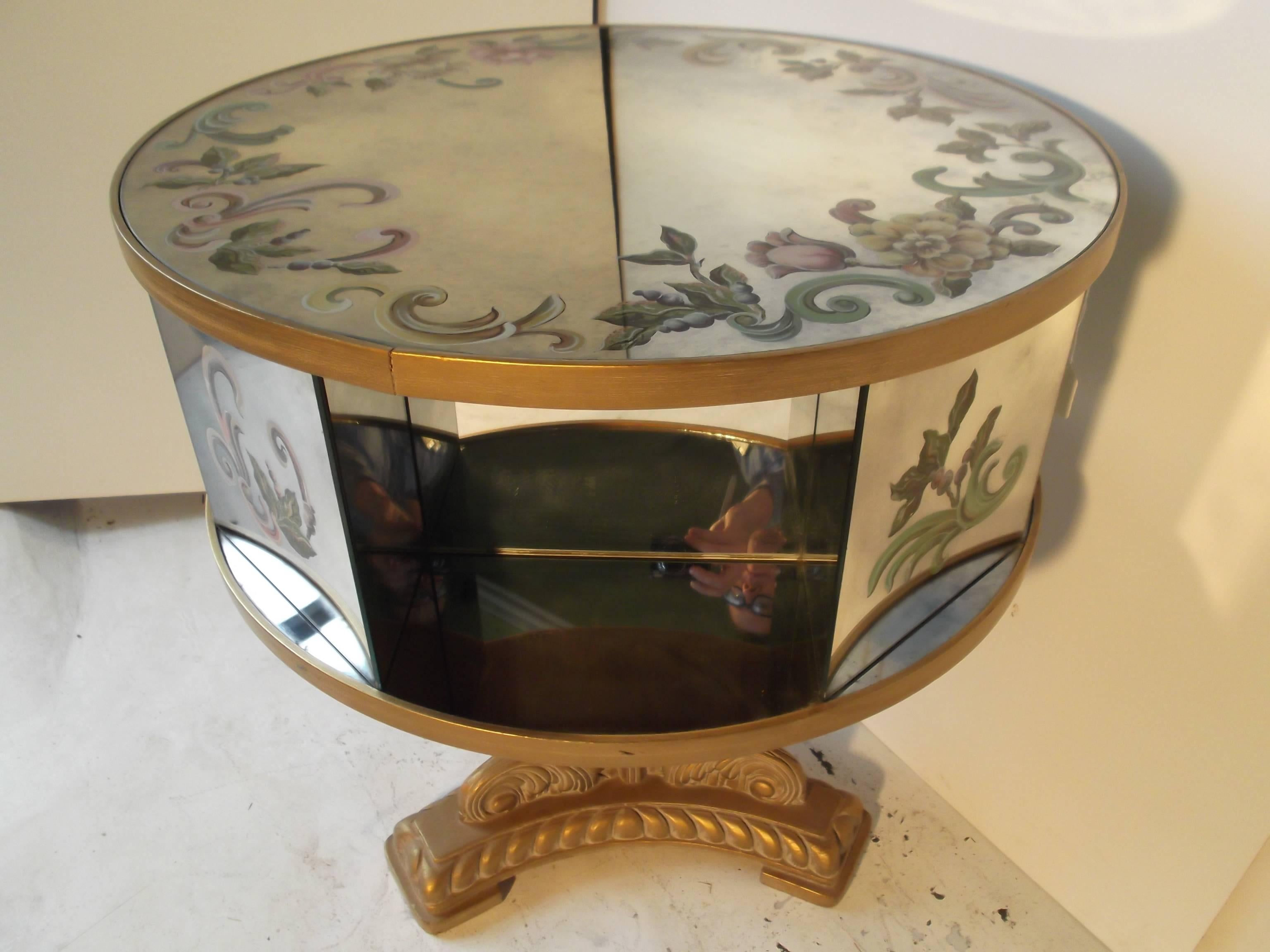 This is a wonderful vintage rotating drum table. It has beautiful reverse painted foliage to top and four side panels. The mirror is purposefully clouded around the paint detail. The base is carved wood, painted good, with leaves and rope like edge.