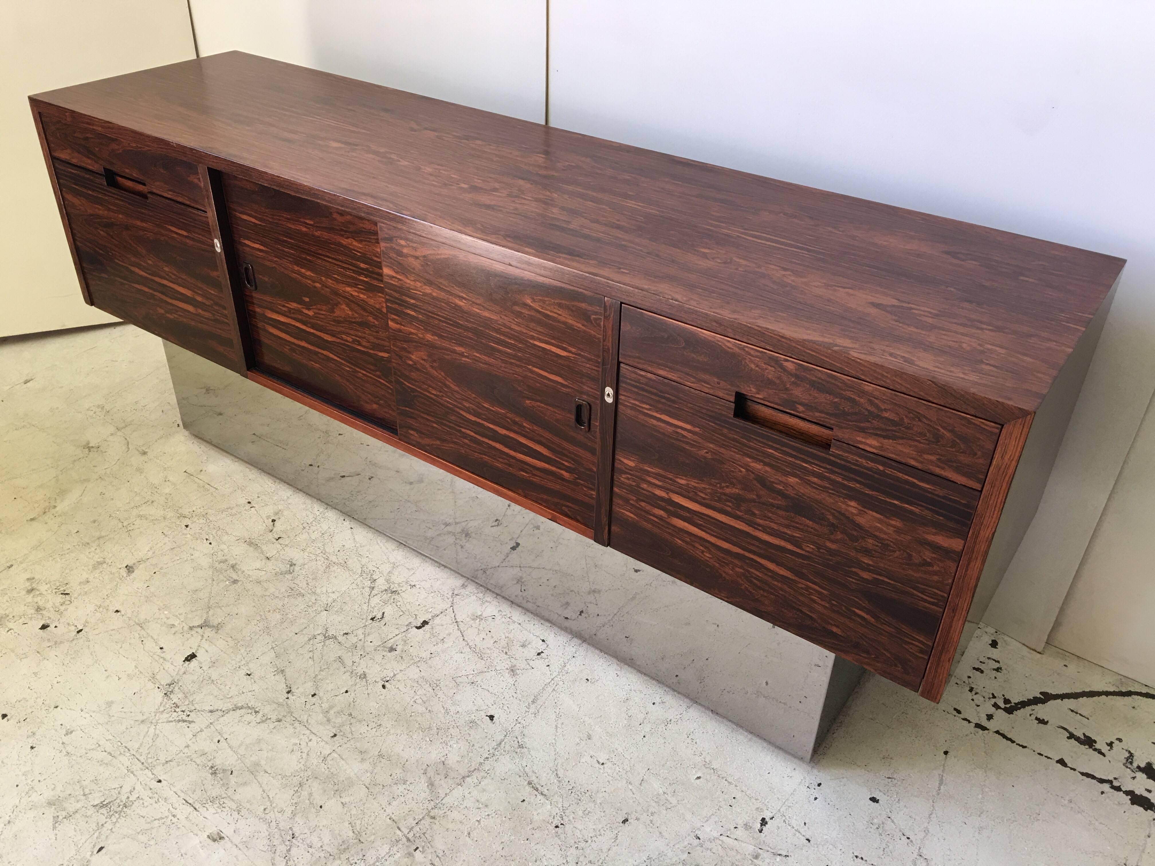 This is an absolutely stunning credenza. It has a figural Brazilian rosewood grain, and effortlessly floats atop a chromed steel box base. It is a vintage piece from circa 1970, attr. to the Pace Collection. Although it resembles many Milo Baughman