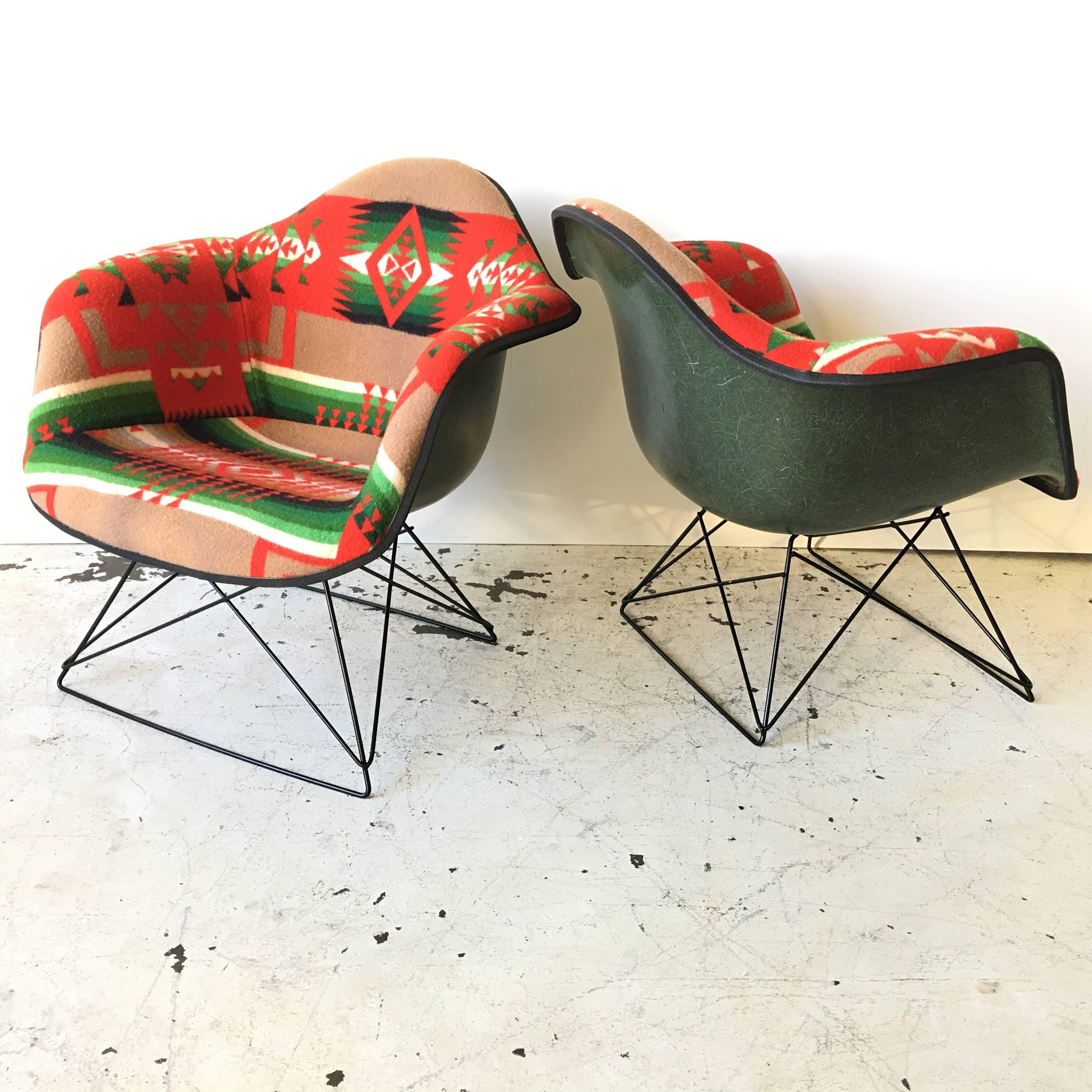 These are vintage Herman Miller dark green, or olive fiberglass armchairs. They have been redone in a vintage Pendleton wool Blanket, with a Native American Indian pattern, in reds, and matching green! They come on new production cat’s cradle low