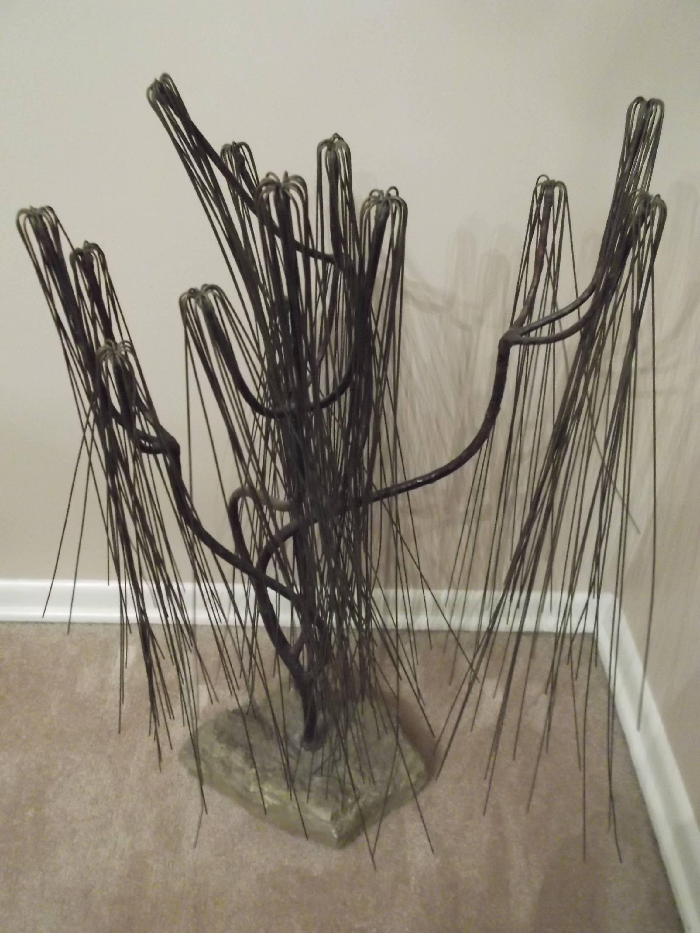 This is a vintage piece, we believe to be from the 1960s era. It is an abstract form of a weeping willow tree. At least that's what my interpretation is. It has many rods welded into groups that splay out as they reach the ground. It is mounted on a