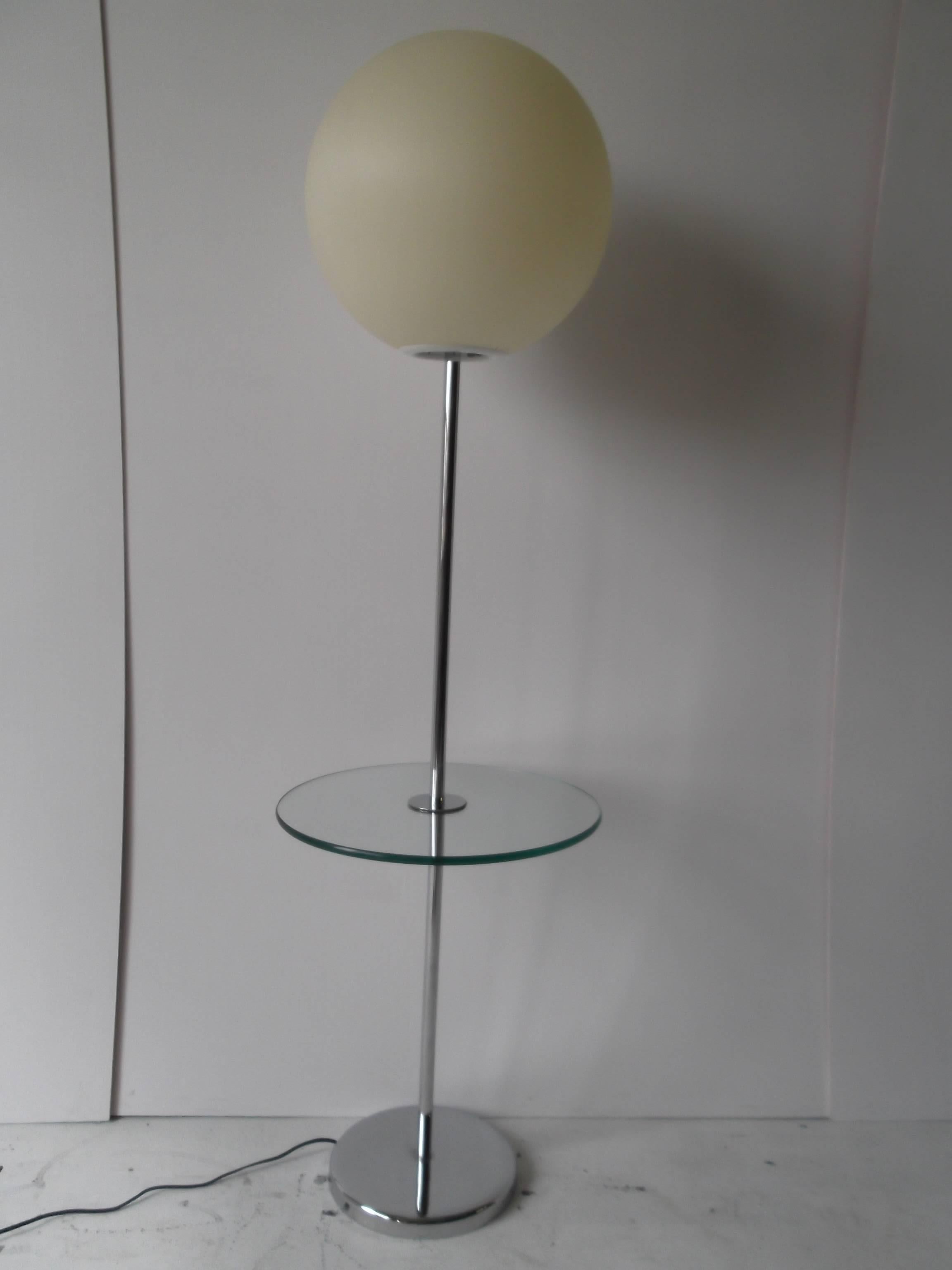 This is an unusual example of a Robert Sonneman Globe or Lollipop floor lamp. It has a tempered glass attached table to the pole, the glass having a green edge. The chrome is excellent and shiny. The globe is brushed matte plastic. There are high