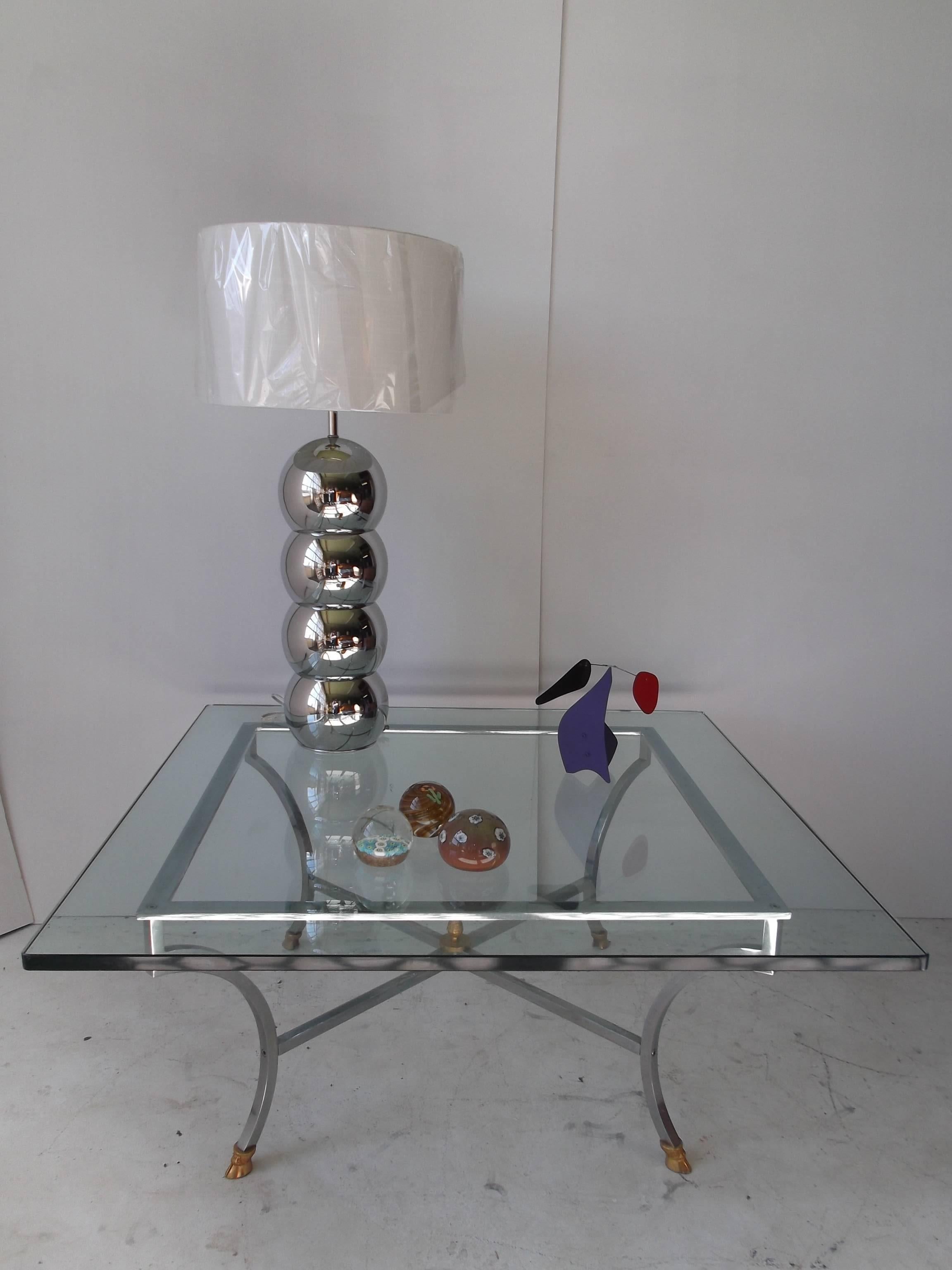 This is a wonderful coffee table from Maison Jansen. It has an architectural steel base with solid brass hoof feet, and a brass pineapple finial to center crossed stretcher beneath. The glass is 3/4