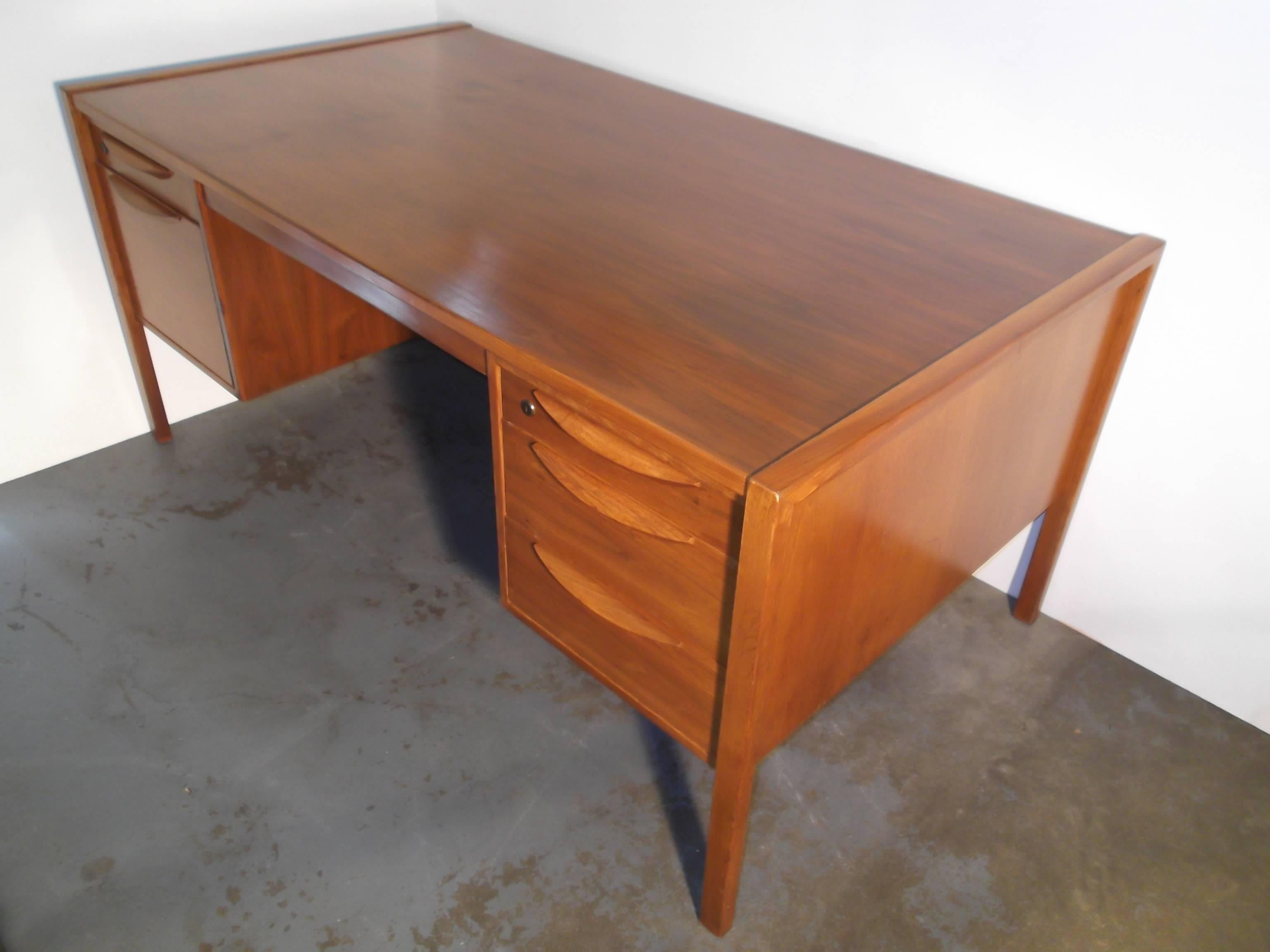 This a nice vintage 1950s desk by Jens Risom. It is in walnut with a nice grain to top especially. It features six drawers with loads of storage, one filing drawer. The drawers are lined in white contrasting formica and feature eyelash pulls in