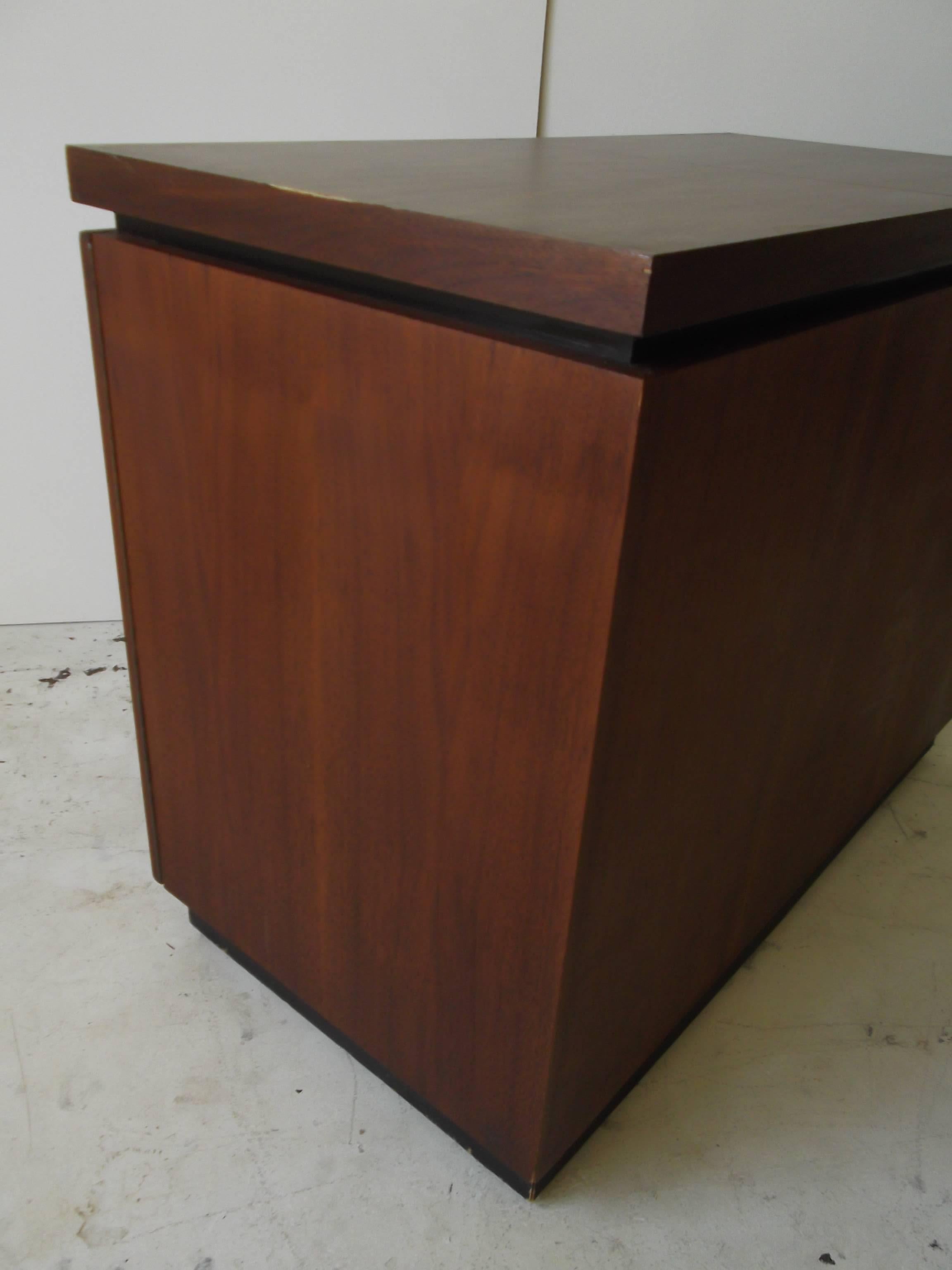 This is a stunning modern bar cart designed by Milo Baughman for Dillingham Furniture. It is in beautiful walnut with nice graining. It has slide open top and front doors, with black and white formica inside, and wood grain formica top for pouring