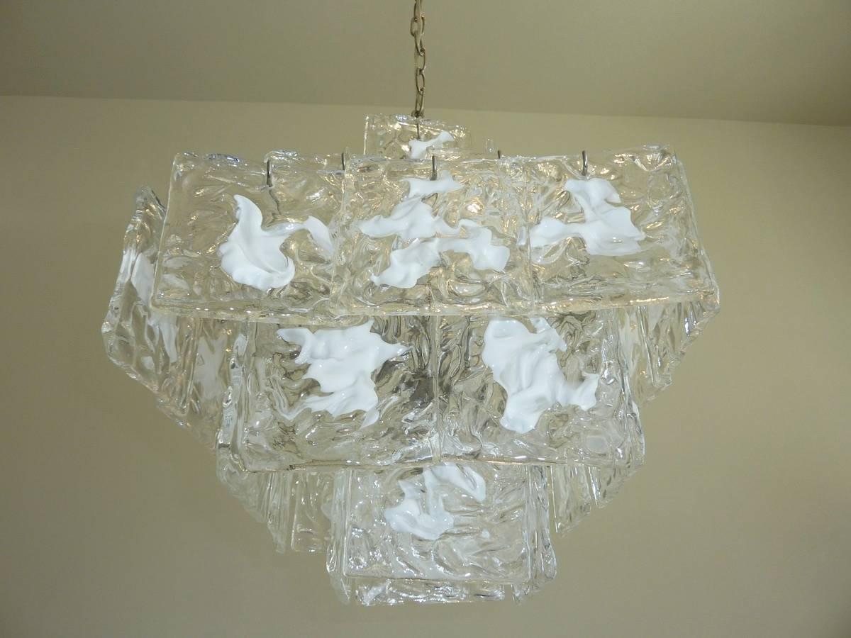 Five-tiered Murano glass chandelier with clear and white textured glass square slabs arranged in a cube shape. Glass squares are suspended from silver tone armature. The 1960s era chandelier has four upwards facing candelabra sockets for European