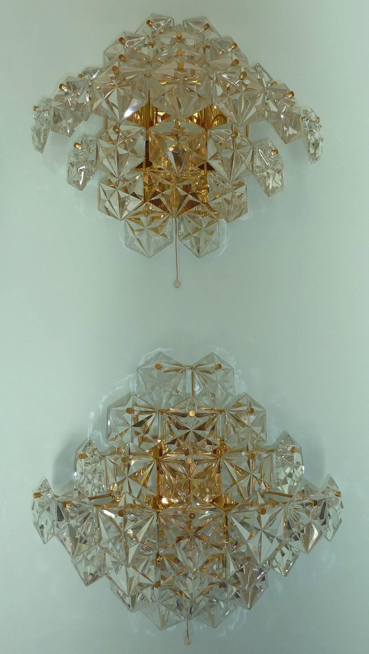 Impressive pair of Kinkeldey sconces with 27 faceted hexagonal crystals on polished brass hardware. The 1960s sconces are semicircular in profile and have an overall diamond shape. There are three sockets; two facing downward, one facing upward.