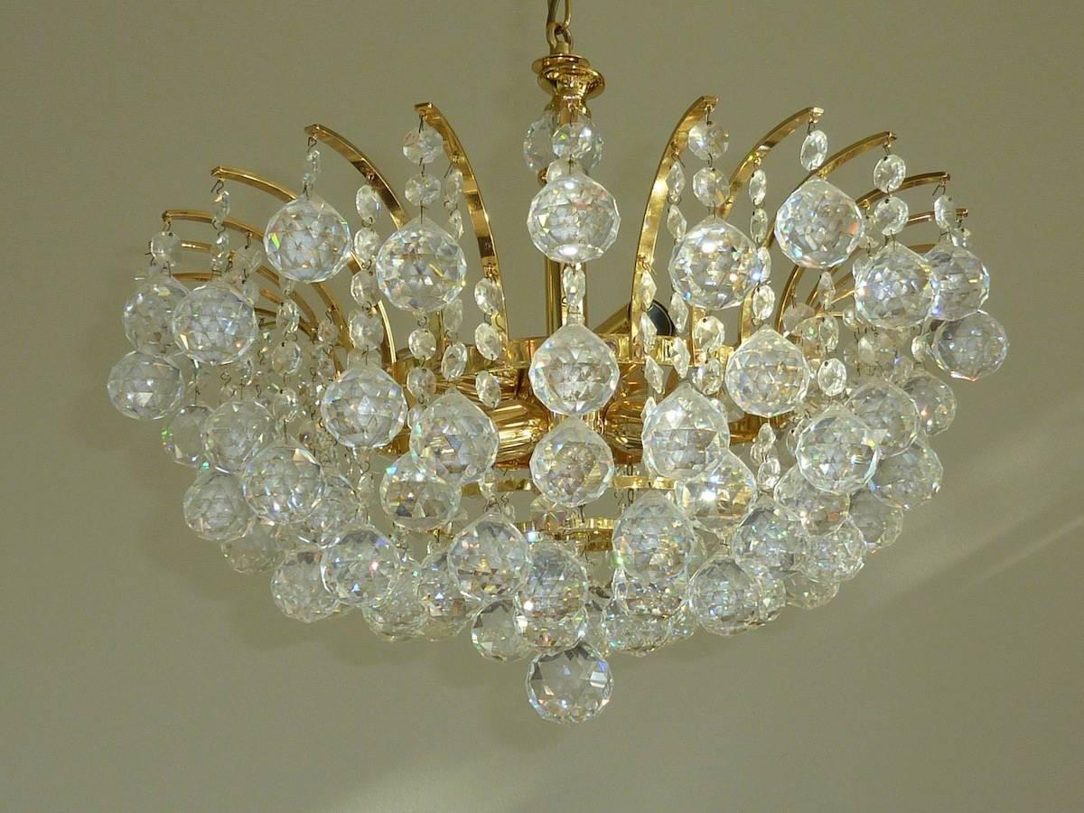 This glamorous Hollywood-Regency style chandelier was made in Austria in the 1970s. It has Swarovski crystals and gold-plated frame. Spectacular Mid-Century crystal chandelier.