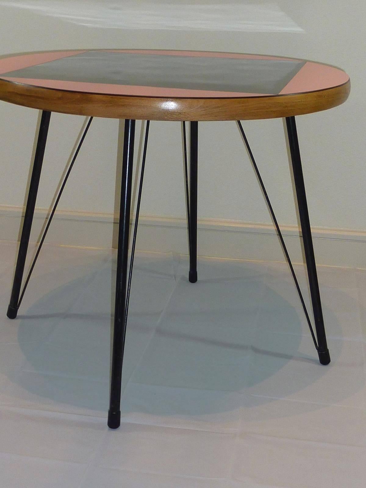 Petite Mid-Century dining table from the Rock a Billy Era. Made of small metal feet and a plywood tabletop. Colored in pink with a black inlay.