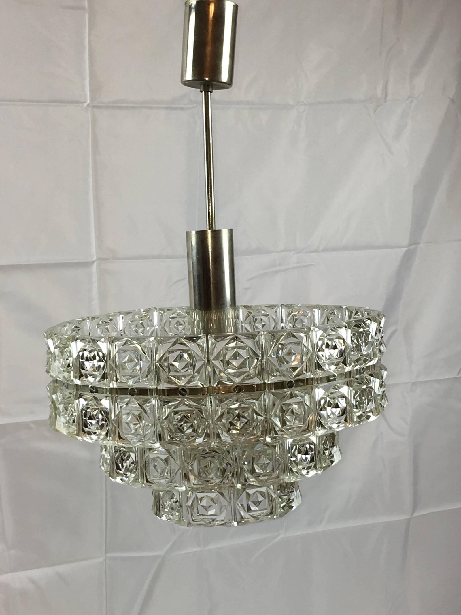German 1960s faceted three-tier crystal Kinkeldey style chandelier with interior lights. The Fixture requires four European E14 candelabra bulbs and a E 27 Edison bulbs, the four bulbs up to 40 watts each, the Edison Bulb up to 60 watts.