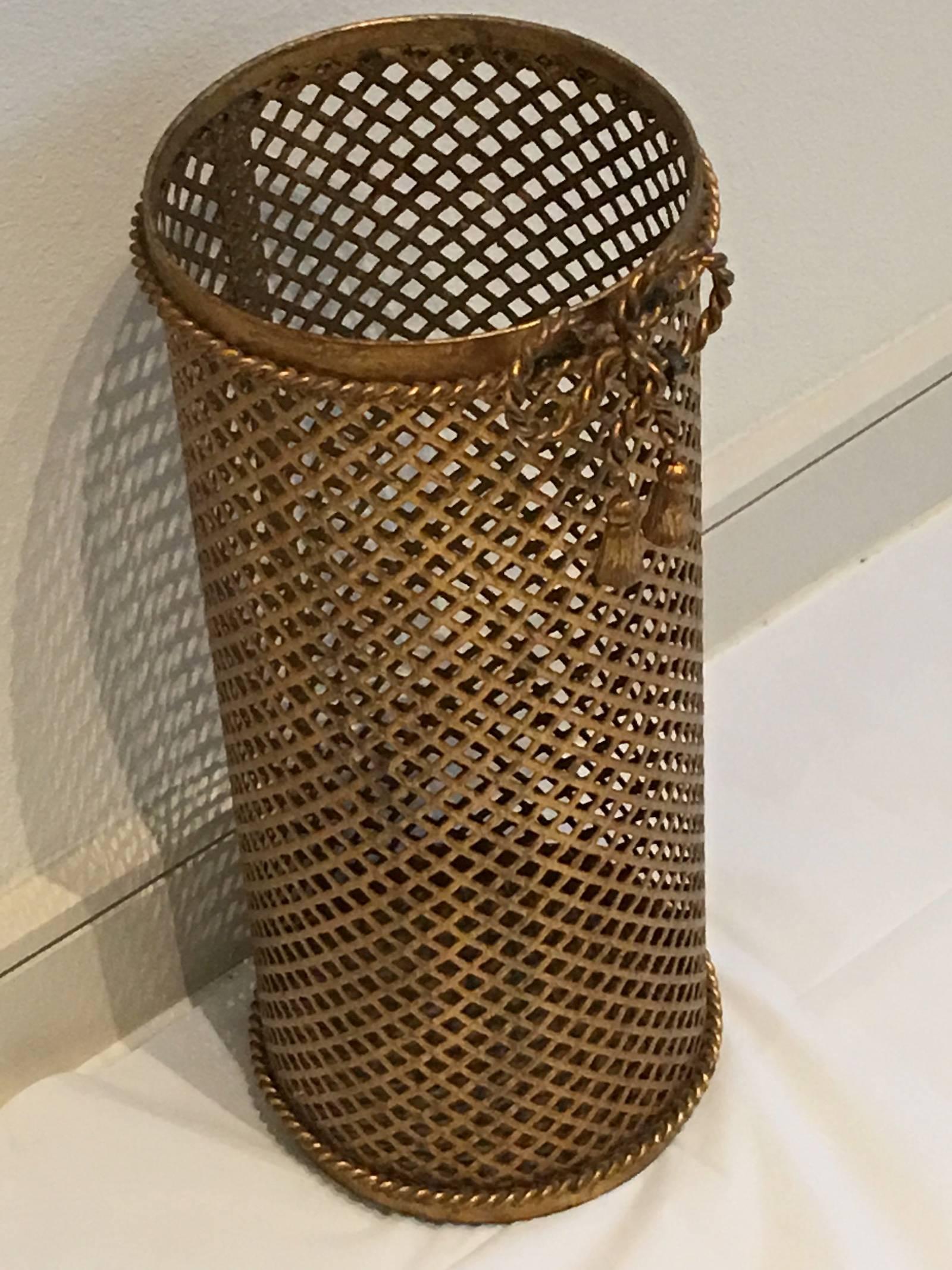 A gilded Hollywood Regency style umbrella stand made in Florence, Italy, circa 1950 by Li Puma Firenze. The perforated lattice patterned metalwork with bent rope and tassel details finish the piece perfectly.