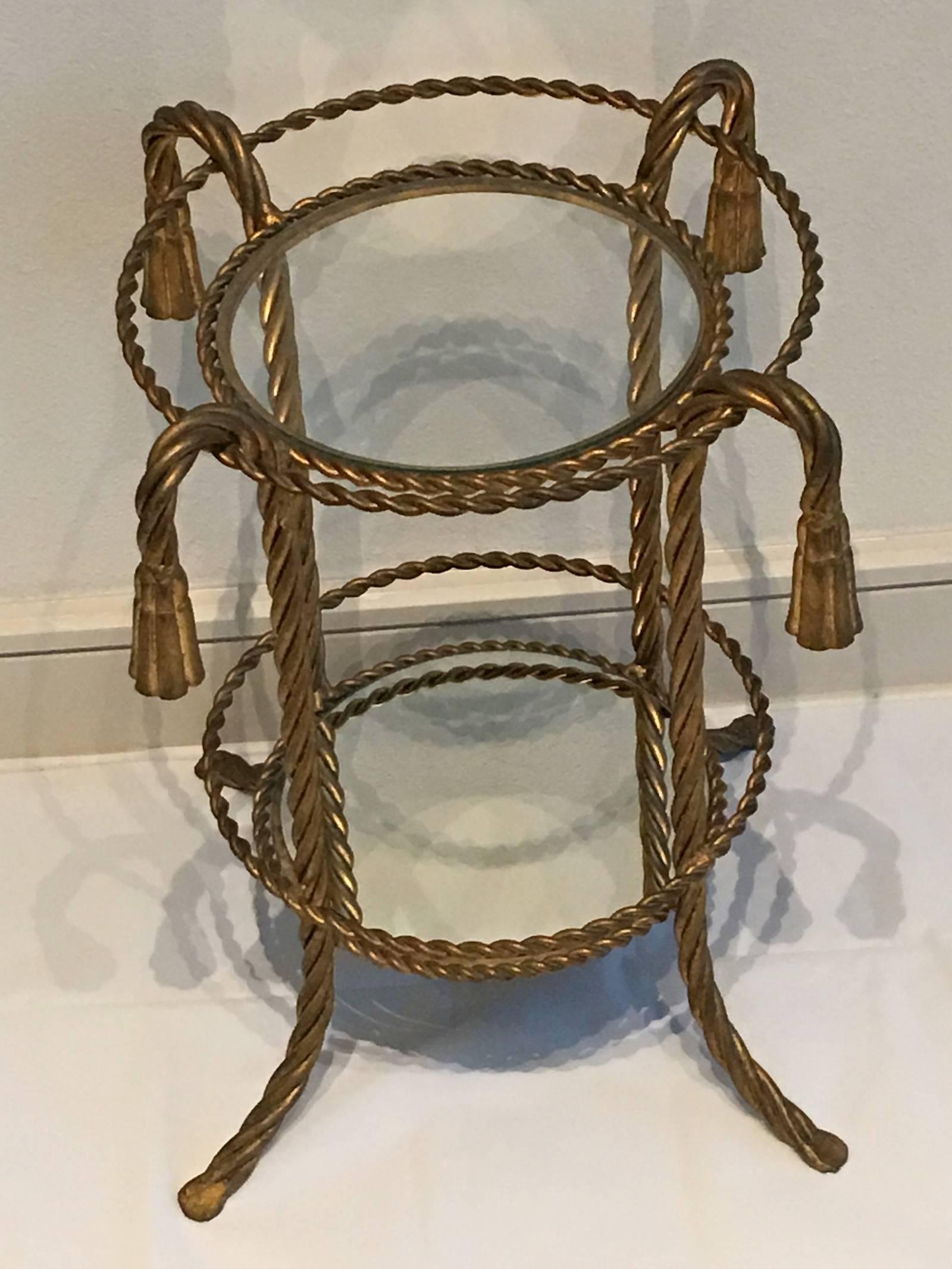 A gilded Hollywood Regency style side table made in Florence, Italy, circa 1950. By Li Puma Firenze. The metalwork with bent rope and tassel details finish the piece perfectly.