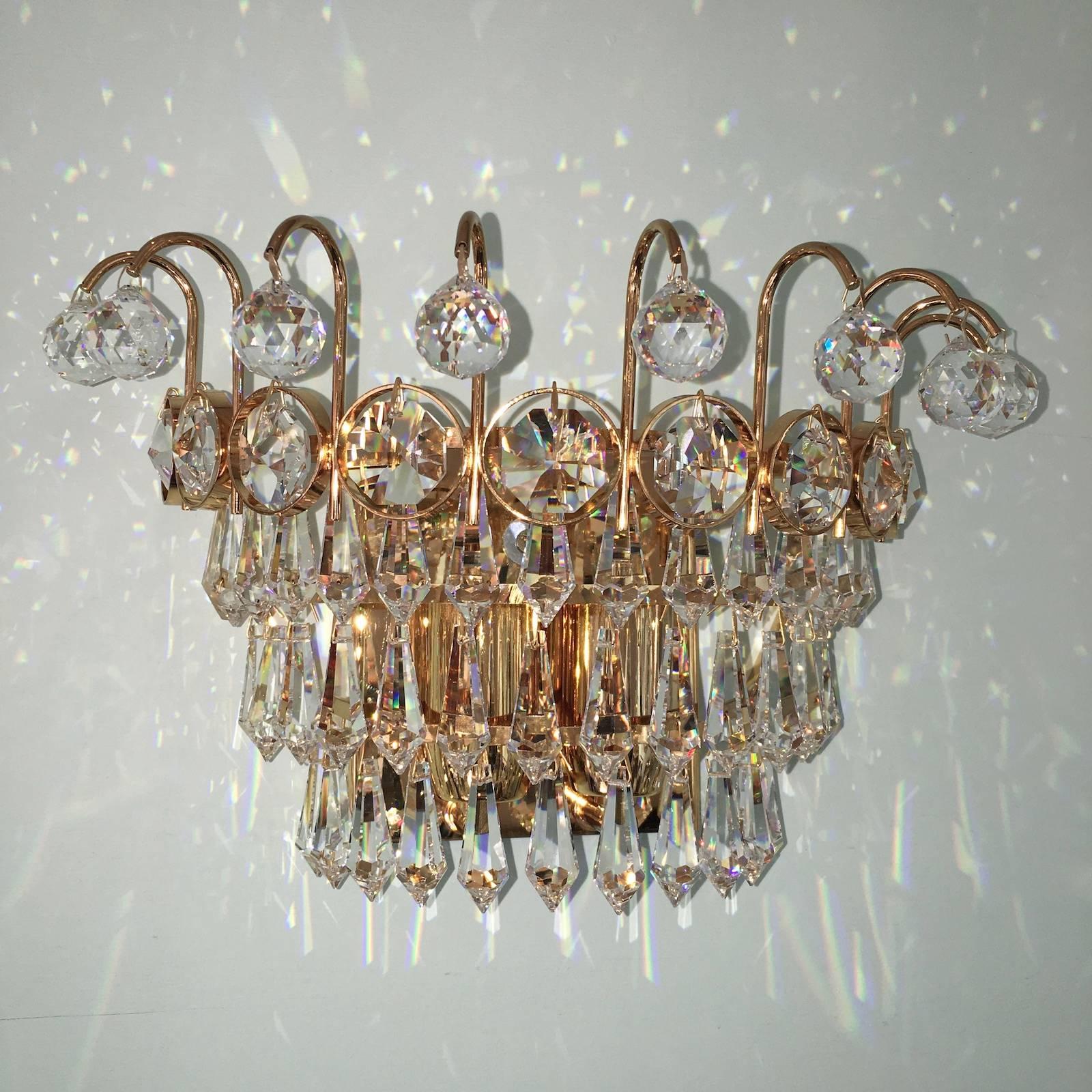 A beautiful pair of handcrafted sconces, manufactured in the 1970s by Palwa of Germany. Made of gold-plated brass with faceted crystal glass petals. Each Fixture requires two European E14 candelabra bulbs each up to 40 watt.